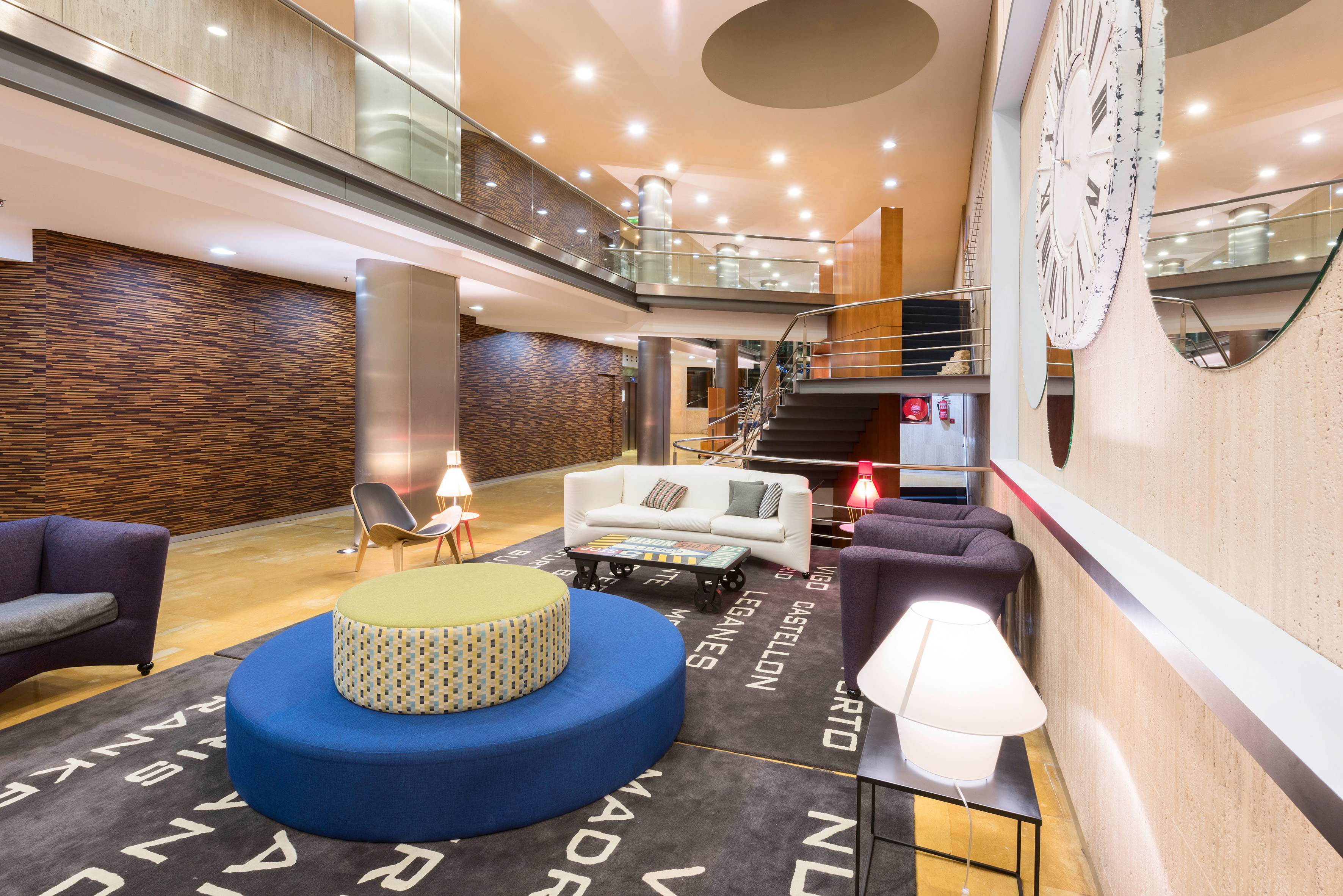 Modern hotel reception lounge with multi-level layout, sofas, and a destination rug.