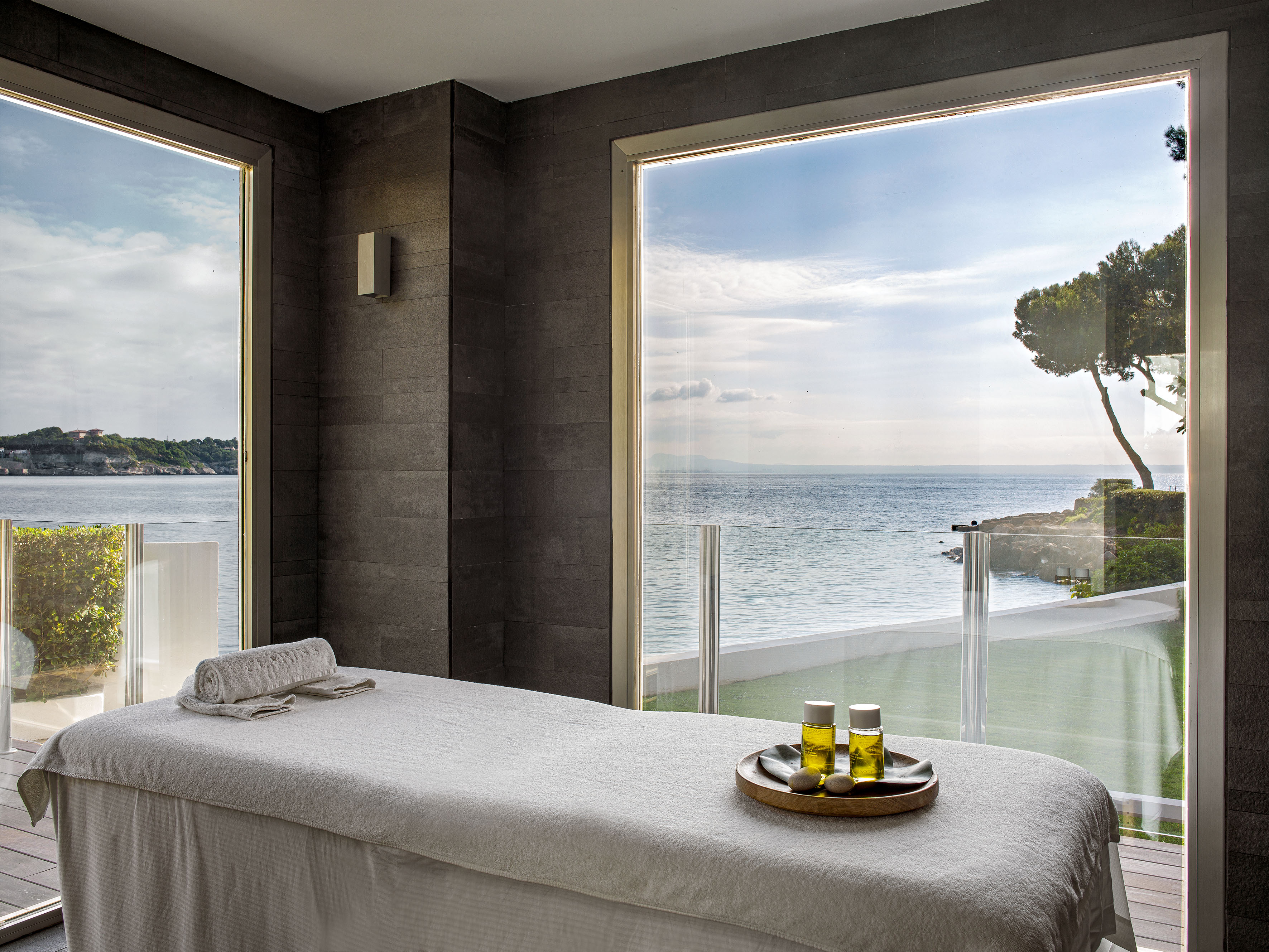 Spa treatment room with ocean view, massage bed, and oils.