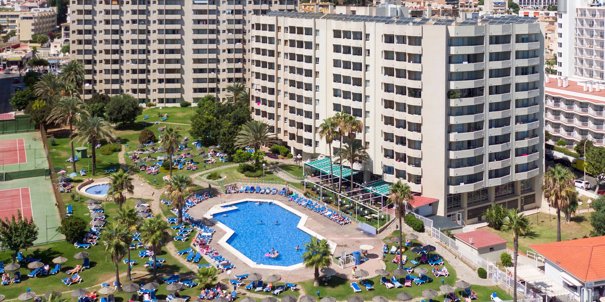 a swimming pool and a large building with mountains in the background