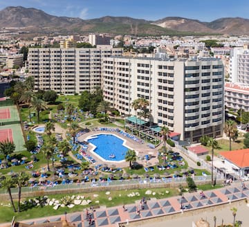 a swimming pool and a large building with mountains in the background