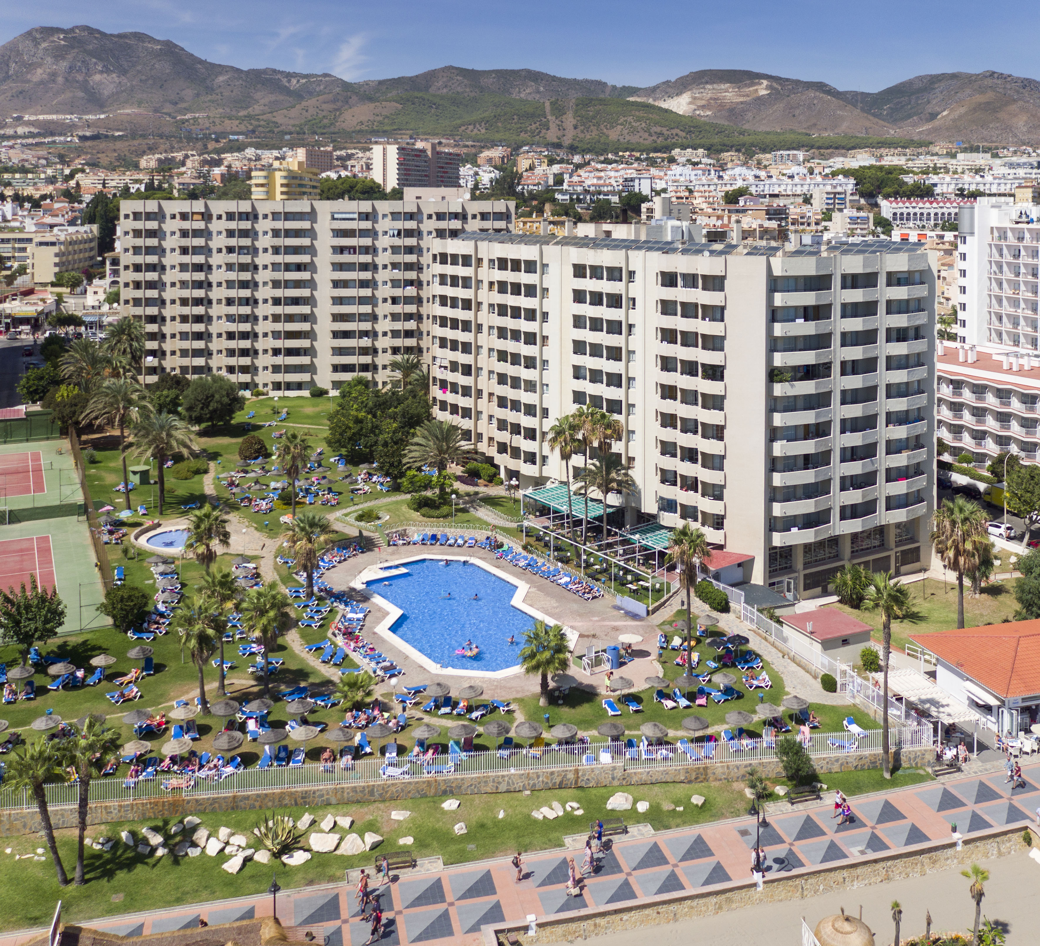 a swimming pool and a large building with mountains in the background
