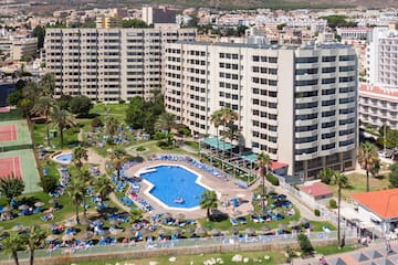 a swimming pool and a large building with mountains in the background