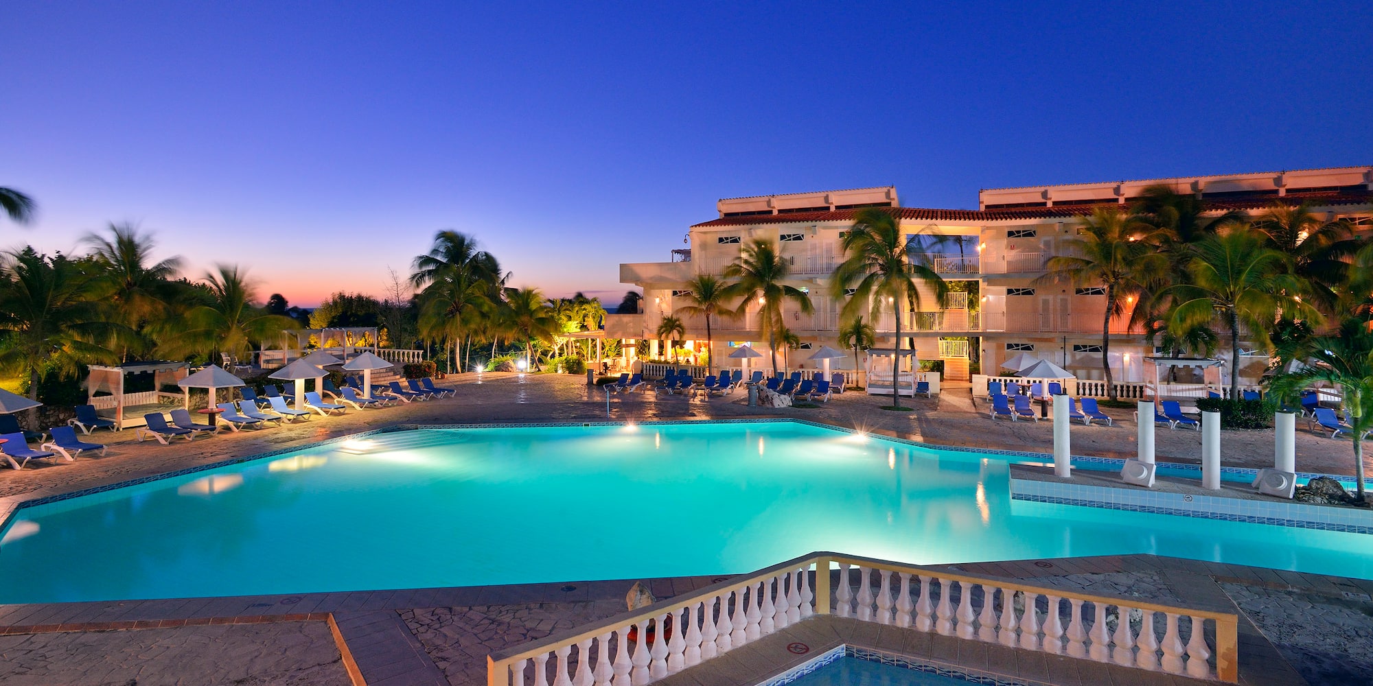 a pool with palm trees and a building