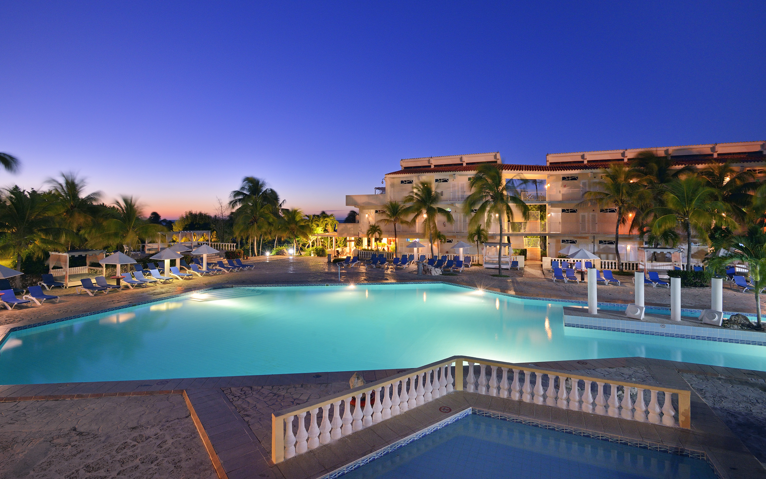 a pool with palm trees and a building
