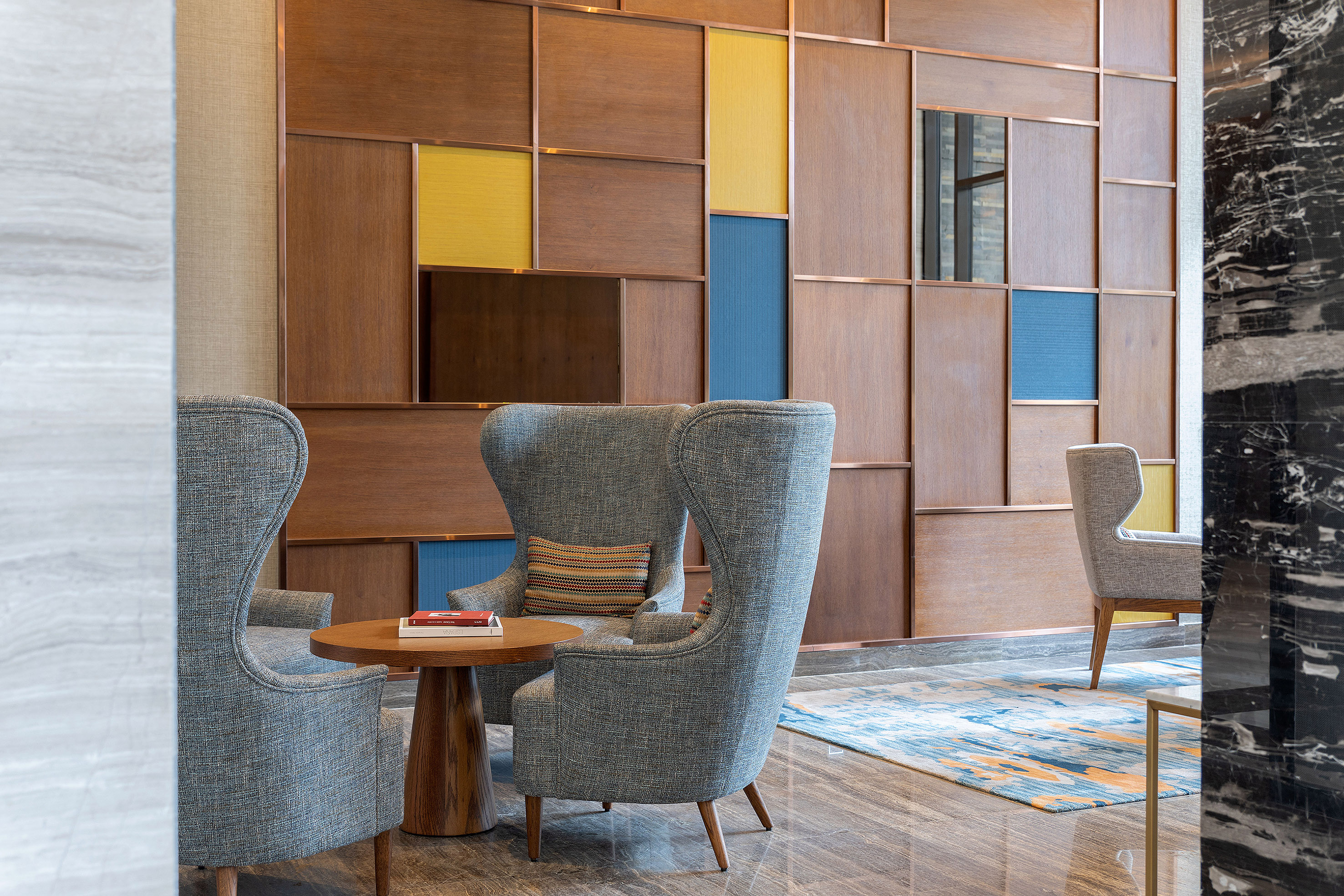 Modern lounge with wingback chairs and geometric wood accent wall.
