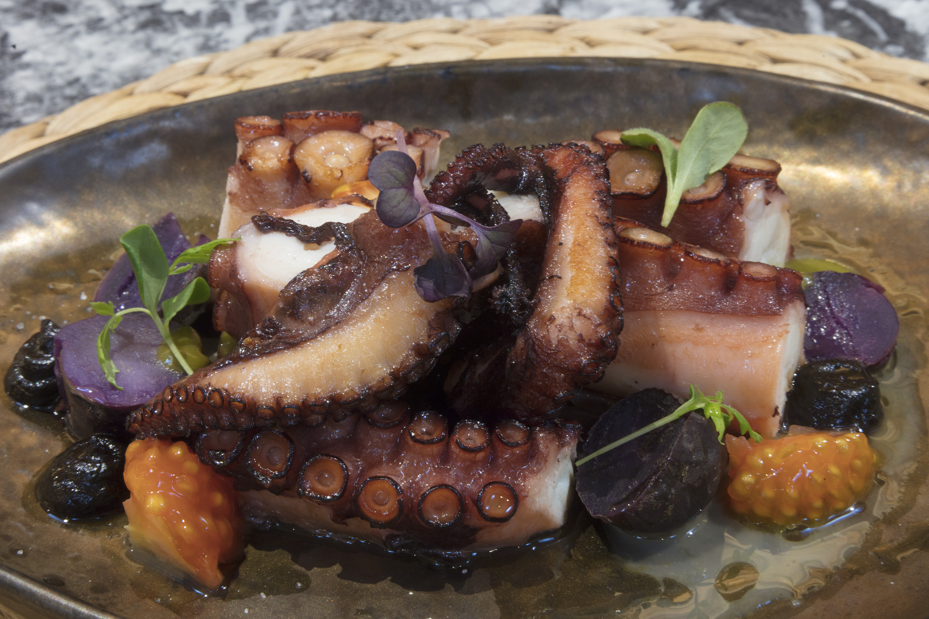 Grilled octopus with crispy tentacles, purple potatoes, and microgreens.
