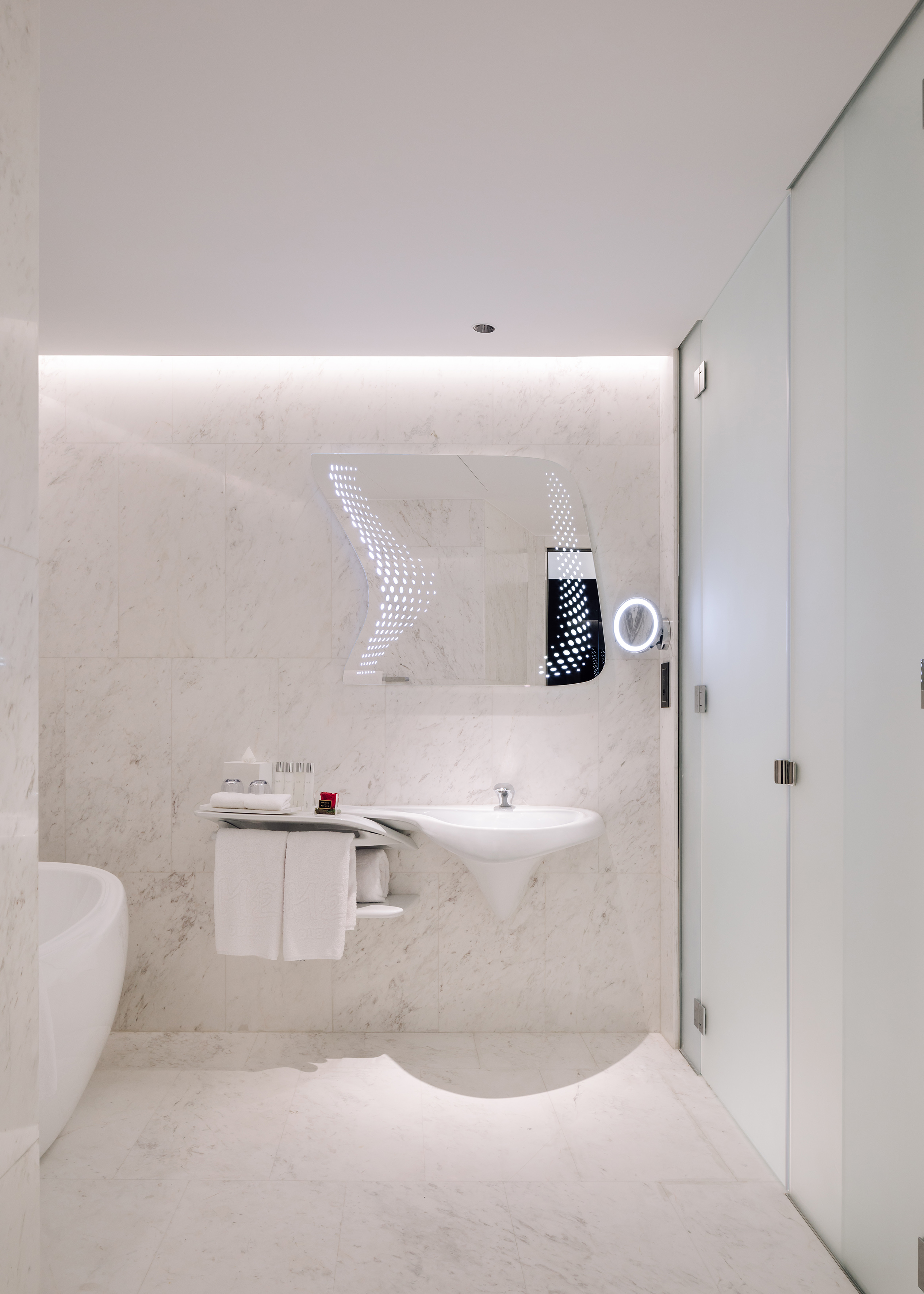 White marble luxury bathroom with modern sink, illuminated mirror, and glass shower.