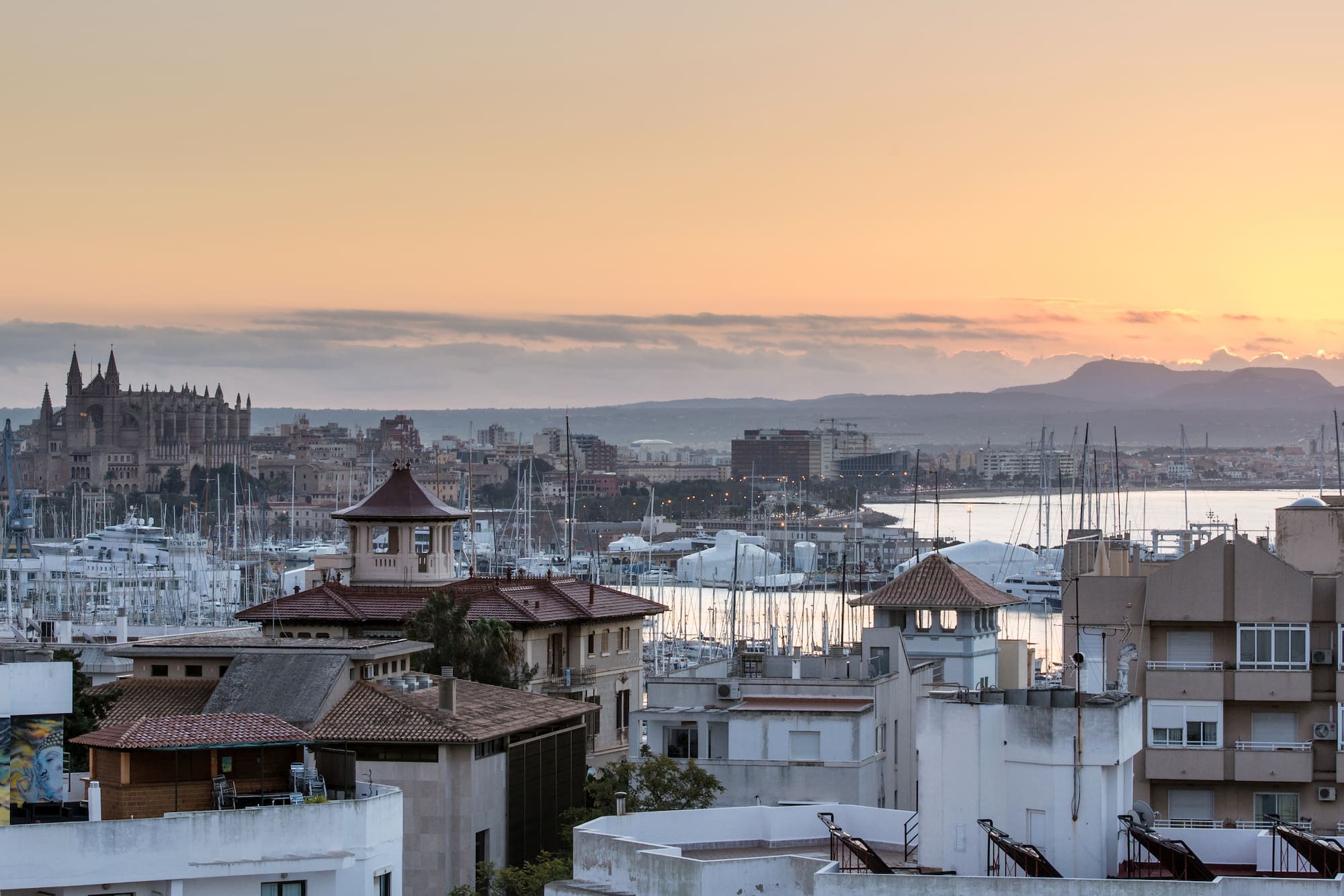 Amanecer en Palma de Mallorca con la Catedral, marina y montañas.