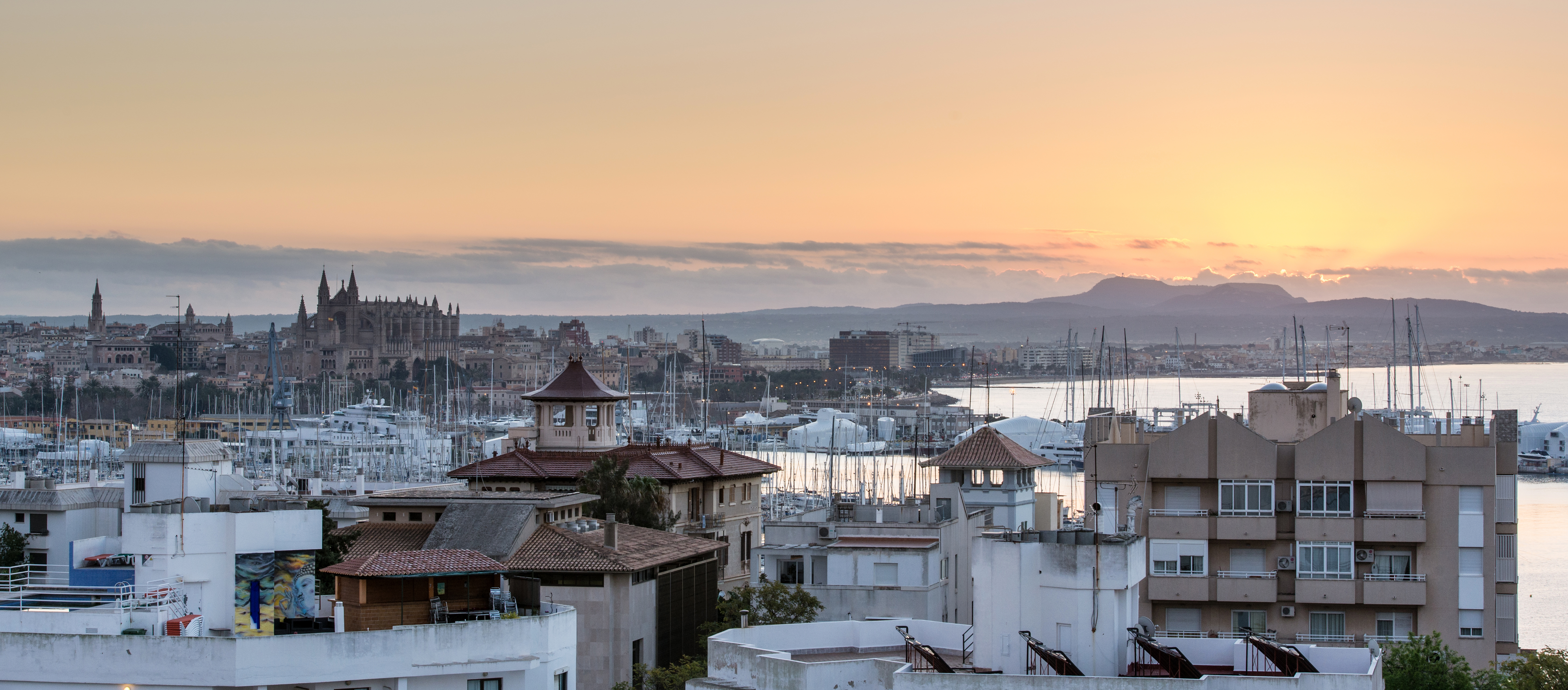 Amanecer en Palma de Mallorca con la Catedral, marina y montañas.