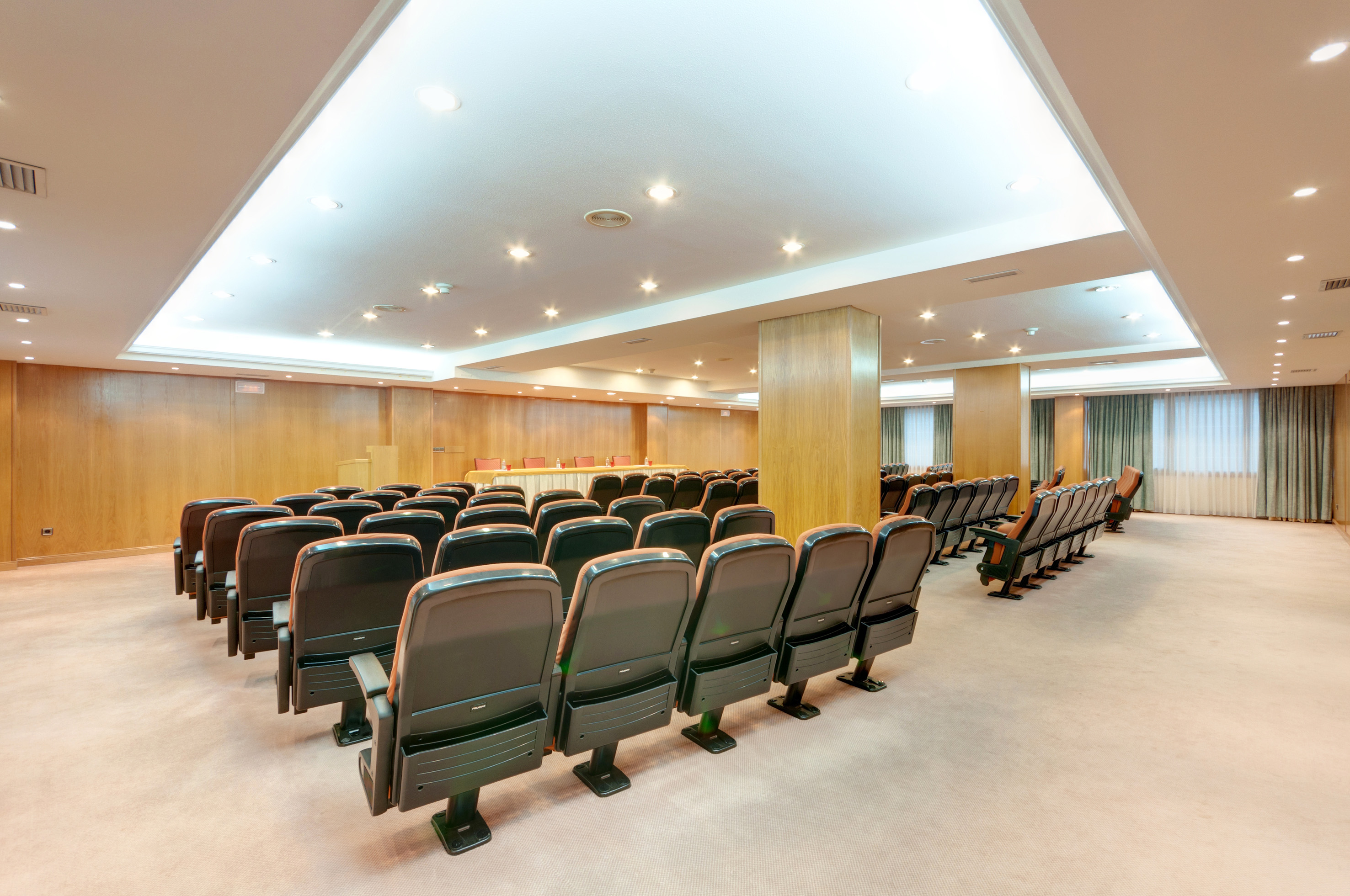 Empty conference room with theater seating, wooden walls, and a front stage.