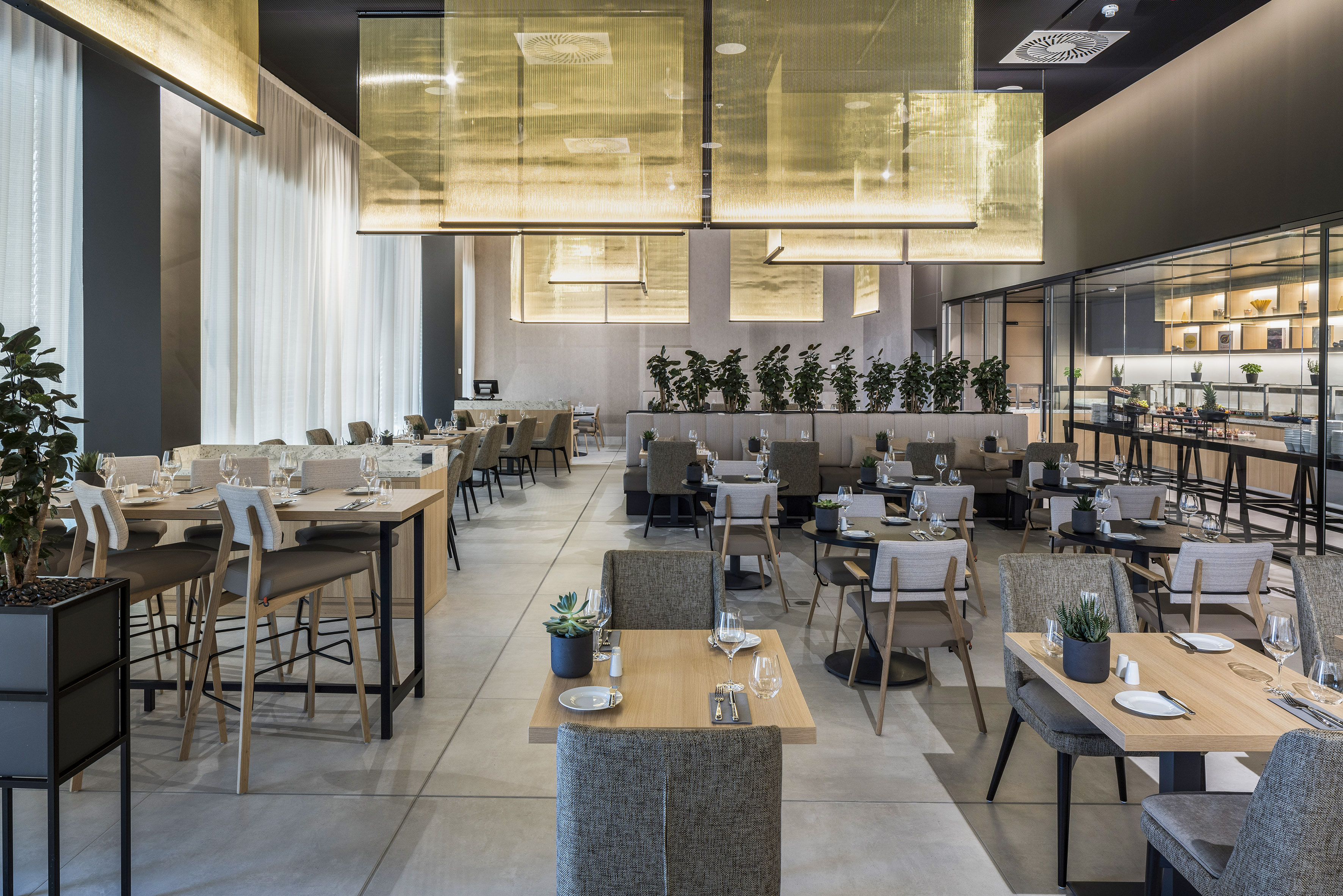 Modern restaurant dining area with set tables, gold lighting, and contemporary decor.