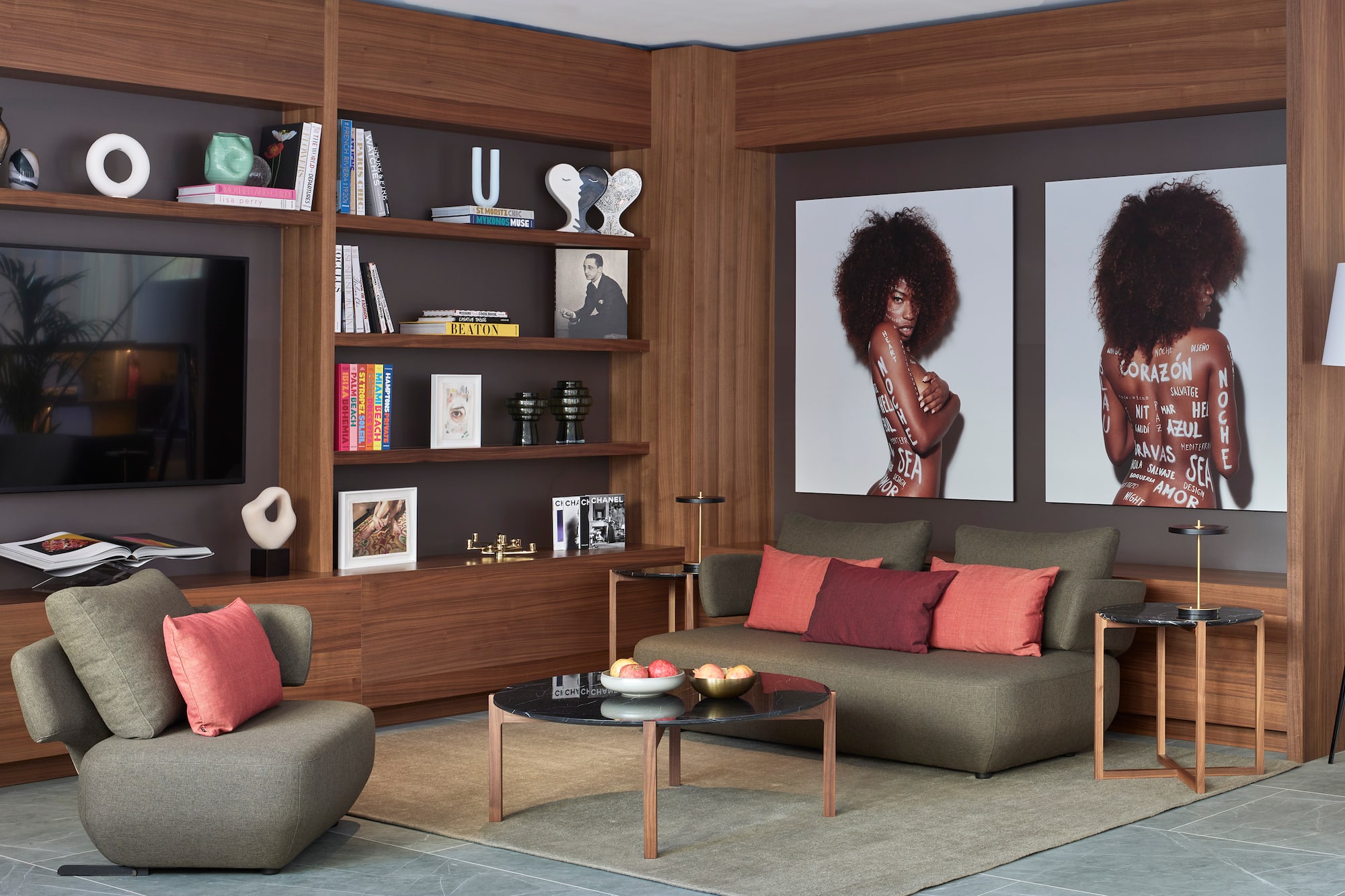 Modern lounge with wood shelves, colorful books, large art prints, green sofa.