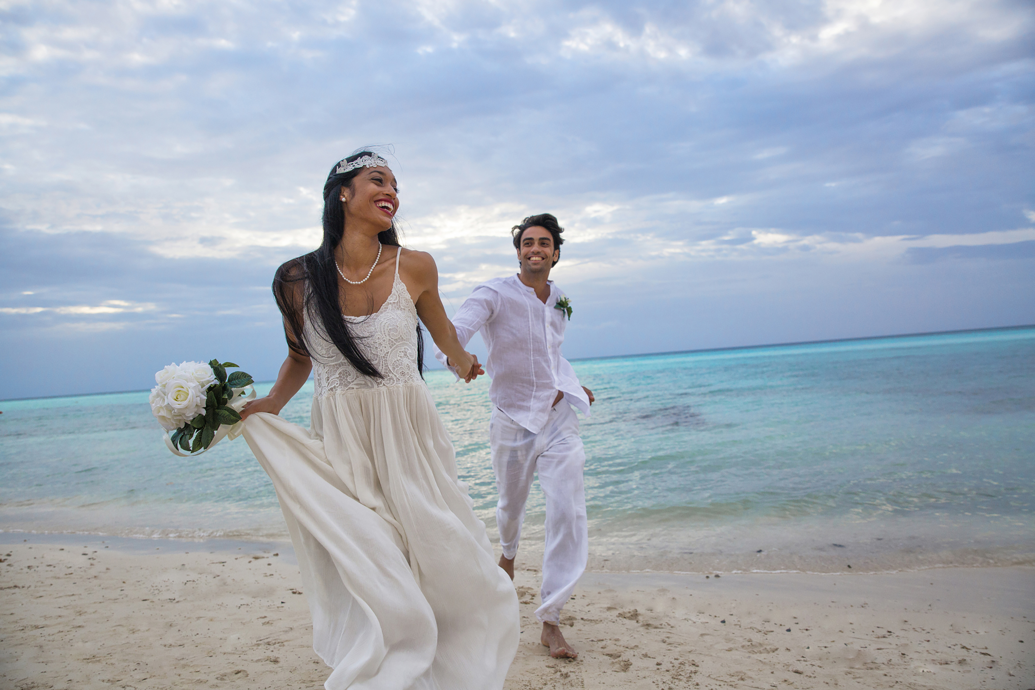 a man and woman holding hands and running on a beach