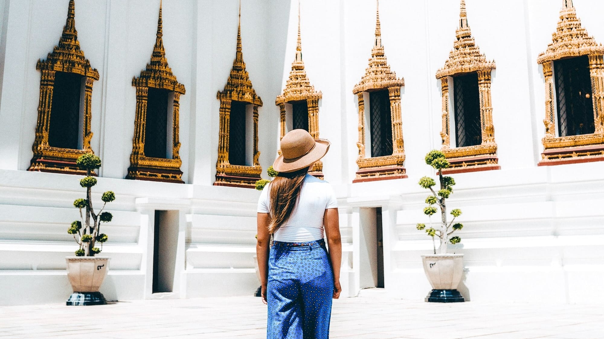 a woman standing in a room with a white wall and windows