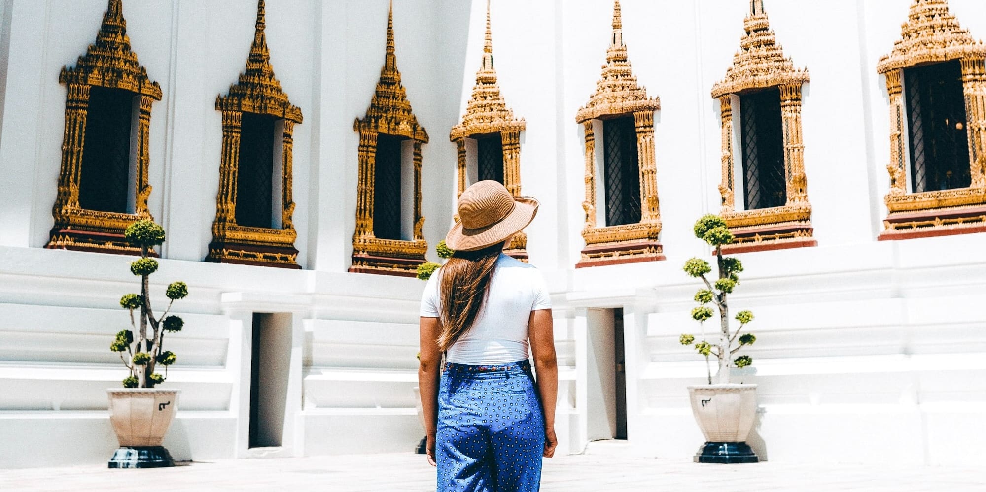 a woman standing in a room with a white wall and windows