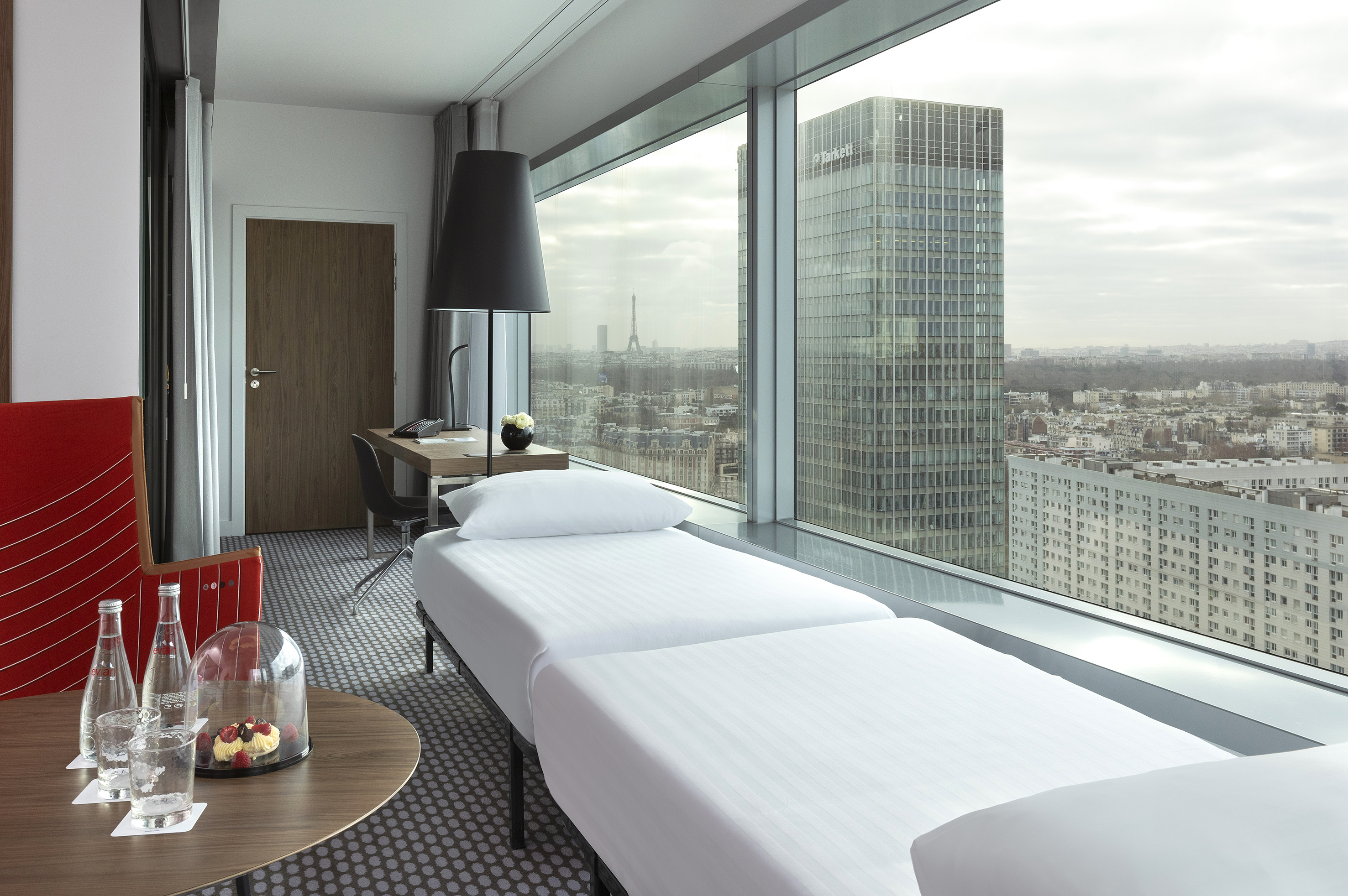 Modern hotel room with Eiffel Tower view, city skyline, and additional bed.