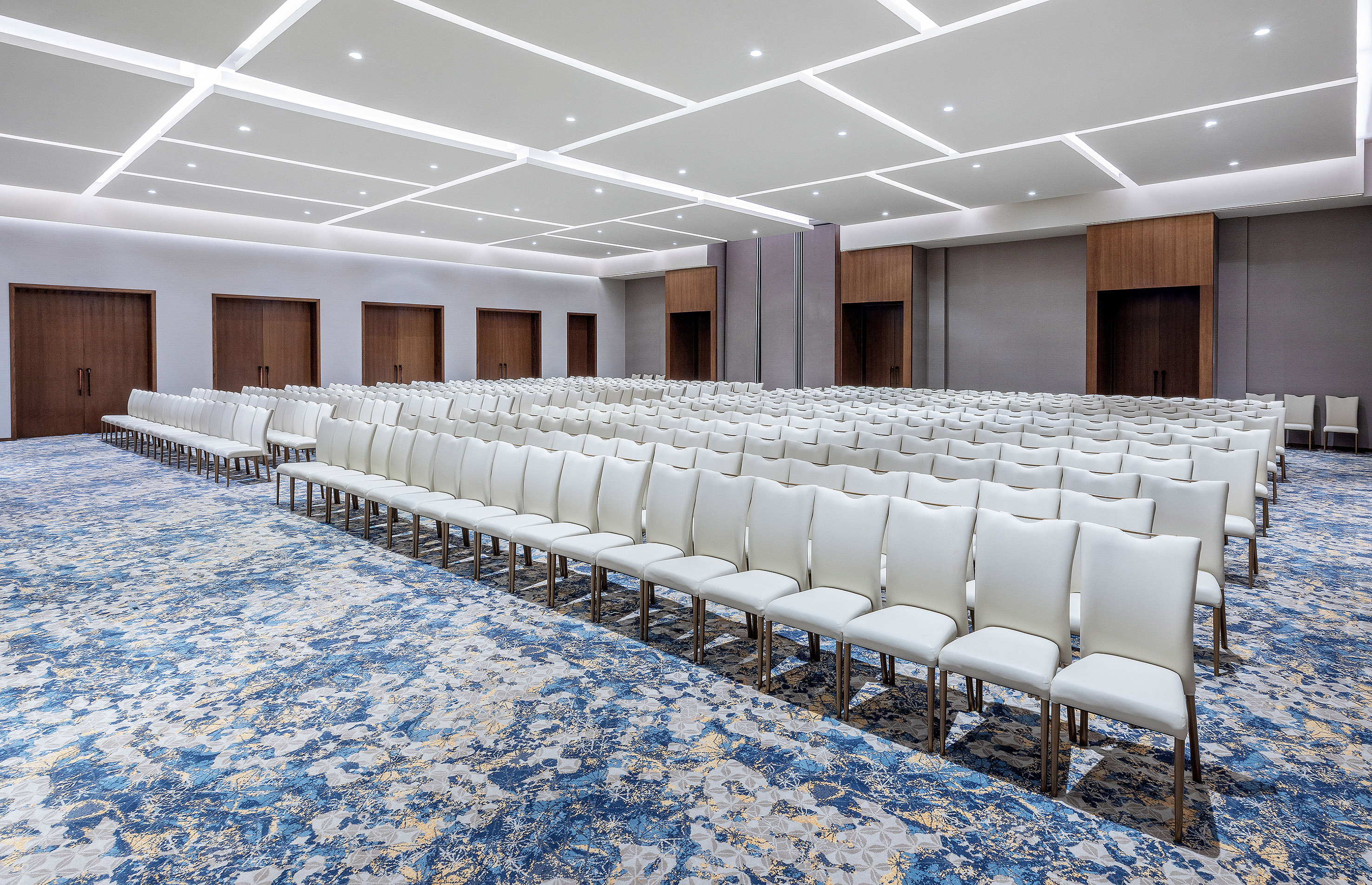 Empty modern conference room with white chairs and blue patterned carpet.