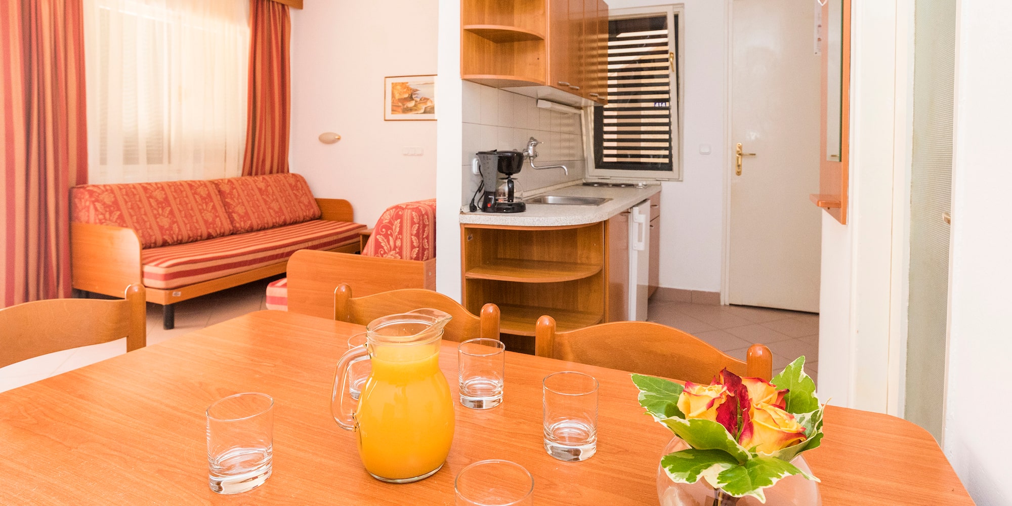 a table with glasses and a vase of juice on it