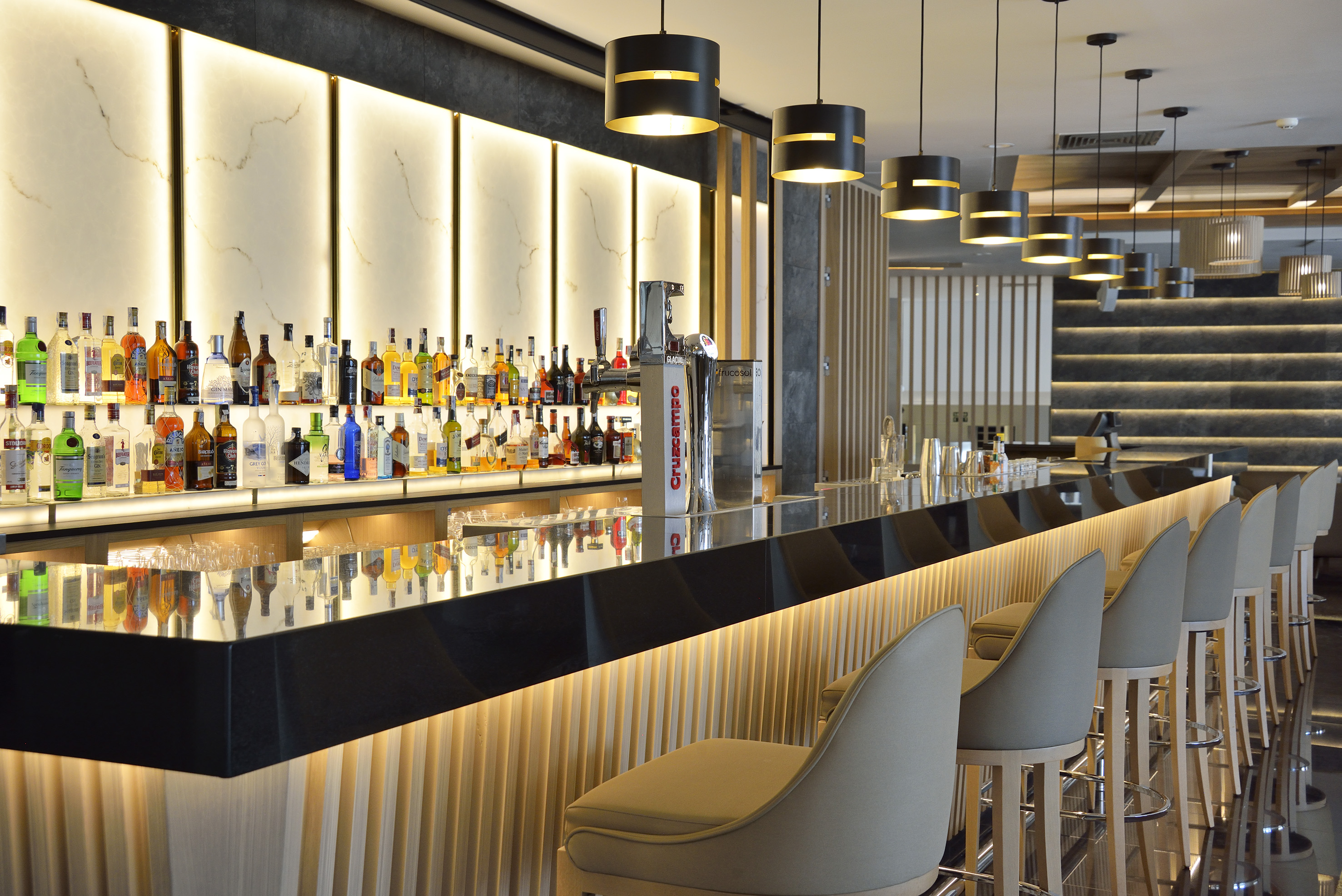 Luxurious modern hotel bar with backlit liquor display and sleek black counter.