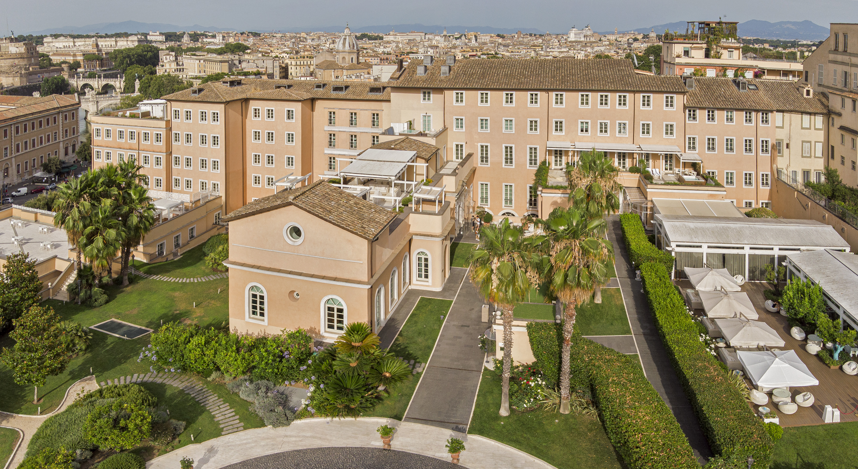 Rome hotel gardens and architecture with city skyline view.