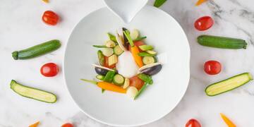 a bowl of vegetables and a spoon of sauce
