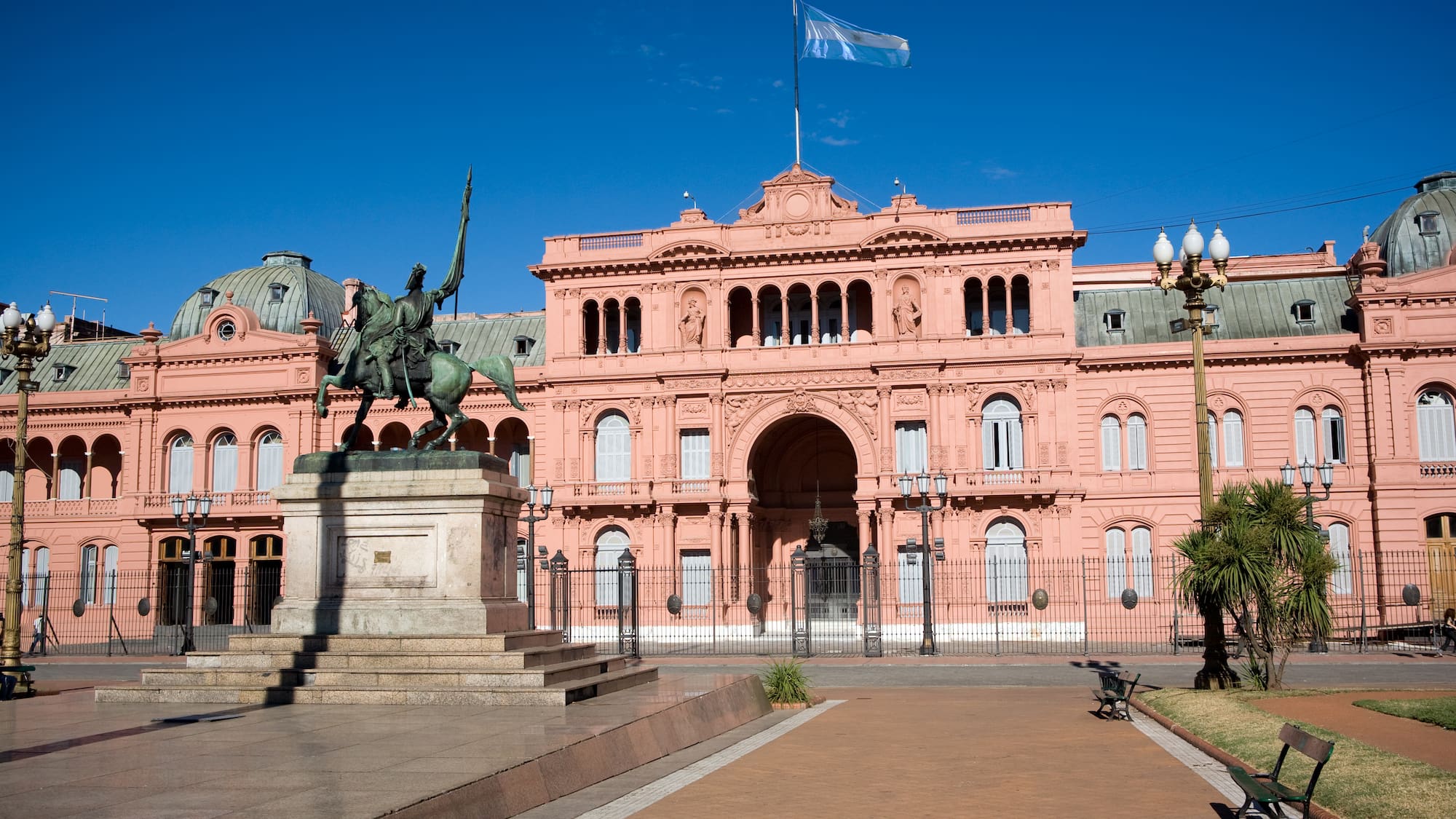 a statue of a man on a horse in front of a pink building with Casa Rosada in the background