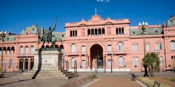 a statue of a man on a horse in front of a pink building with Casa Rosada in the background