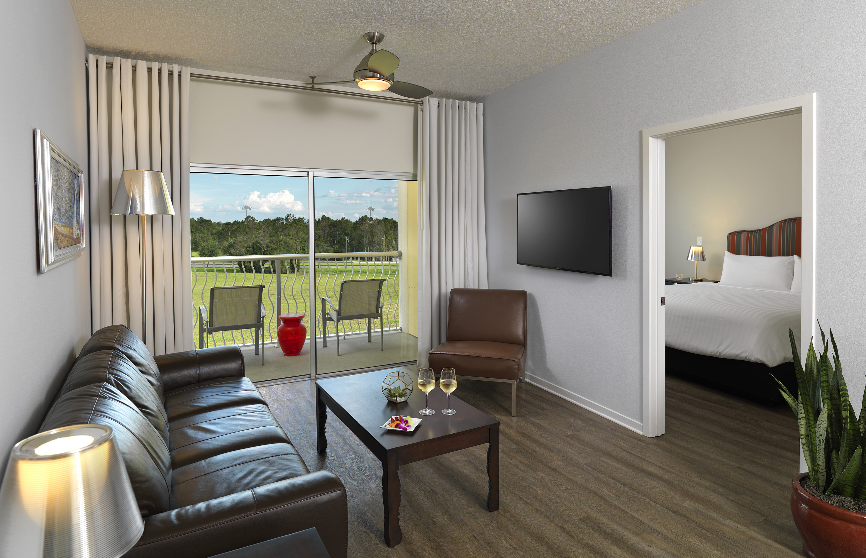 Hotel suite living room with golf course view balcony and bedroom.