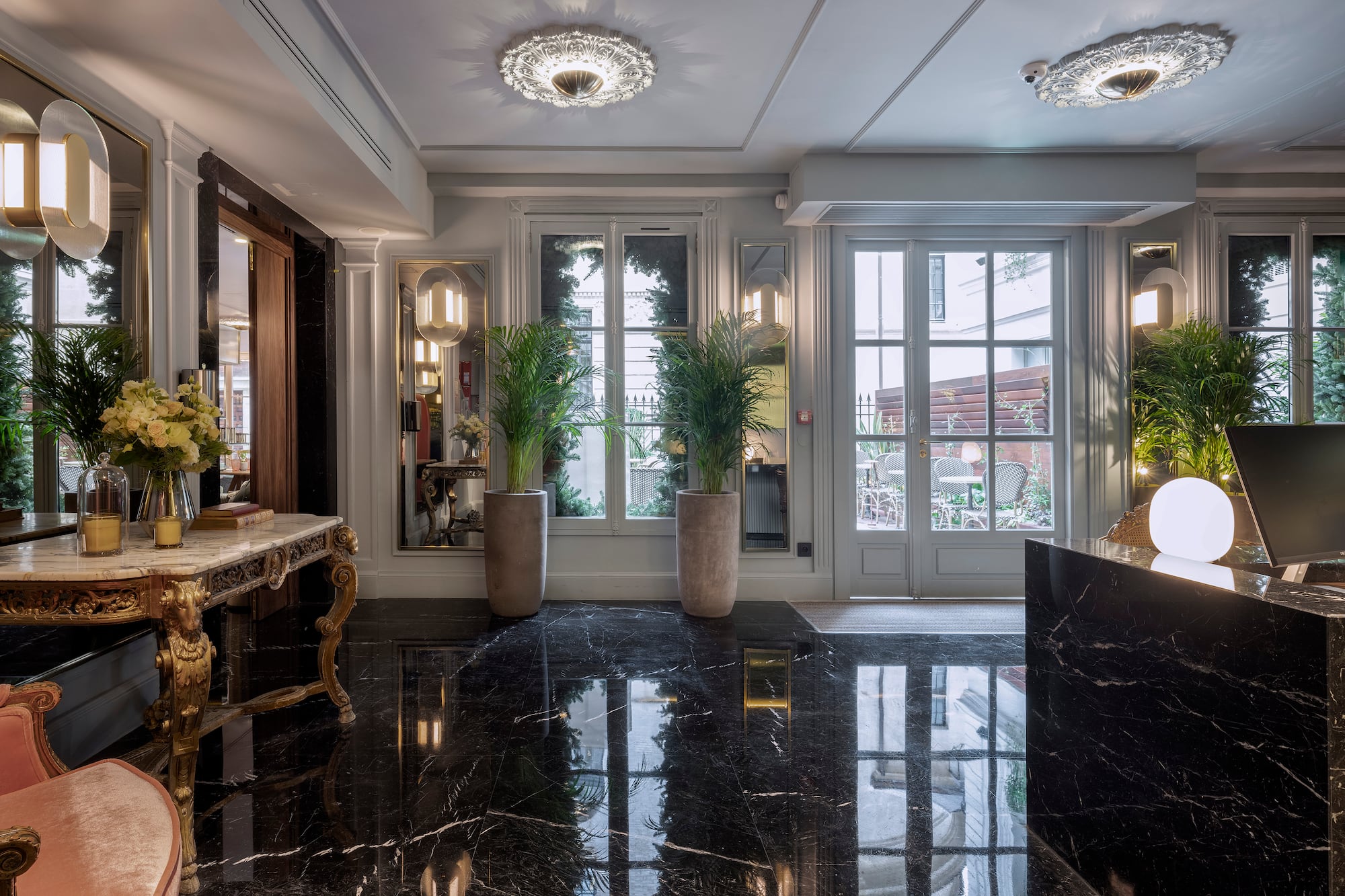 Luxury hotel reception with black marble floor, ornate table, and large windows.