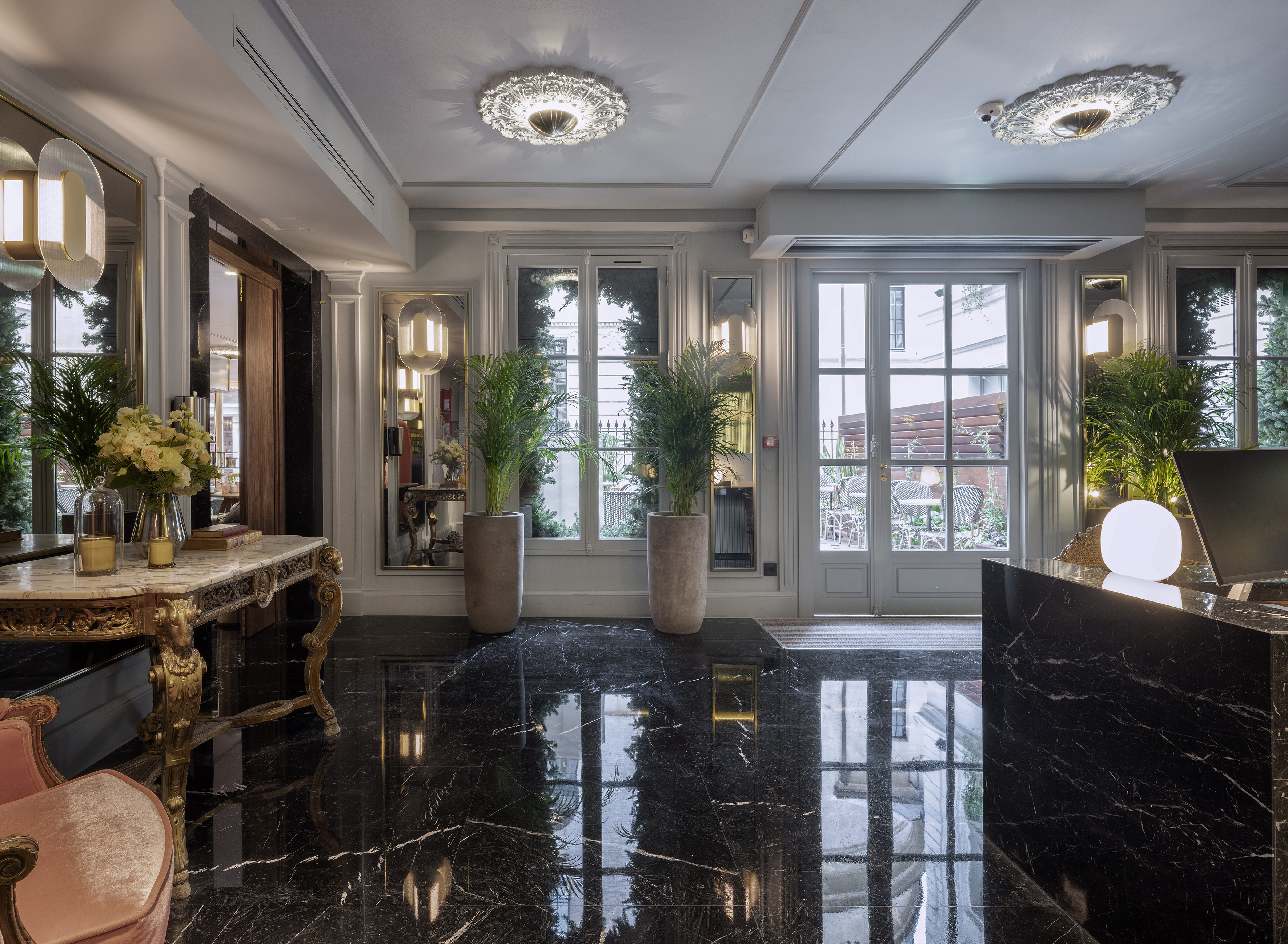 Luxury hotel reception with black marble floor, ornate table, and large windows.