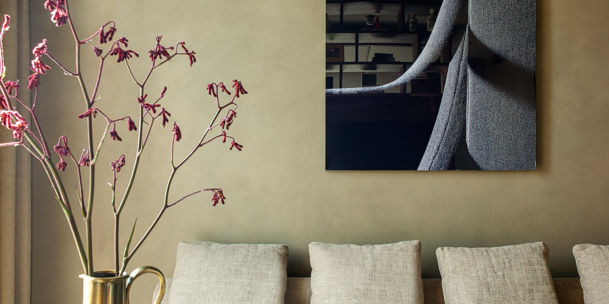 a vase of flowers in front of a painting on a wall