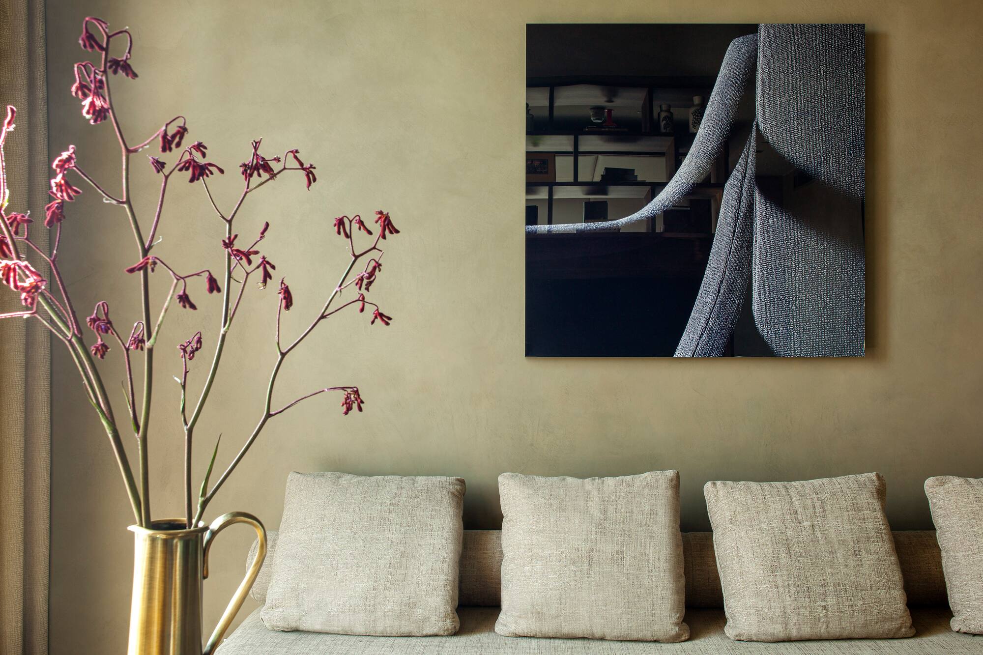 Modern interior with sofa, abstract art, brass vase and red botanicals.
