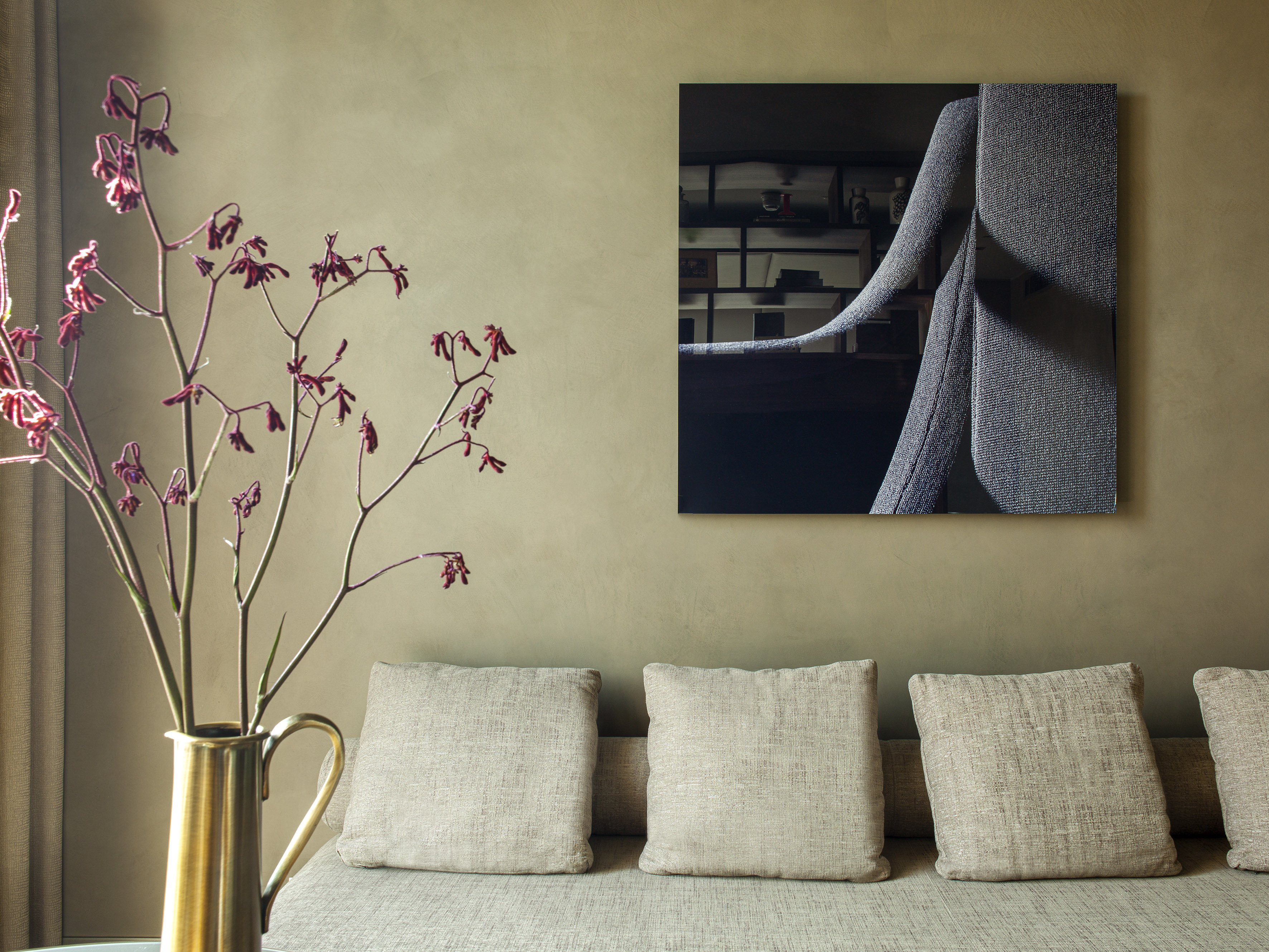 Modern interior with sofa, abstract art, brass vase and red botanicals.