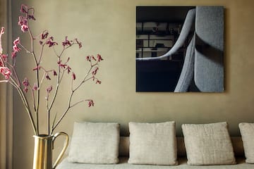a vase of flowers in front of a painting on a wall