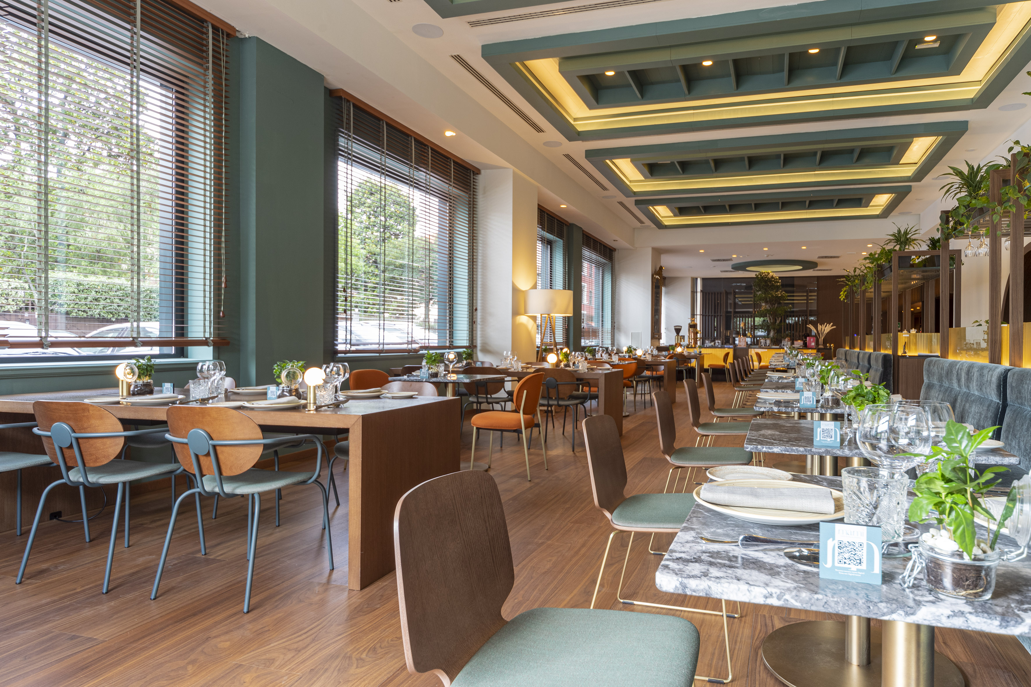 Elegant restaurant dining area with green walls, wooden floors, and set tables.