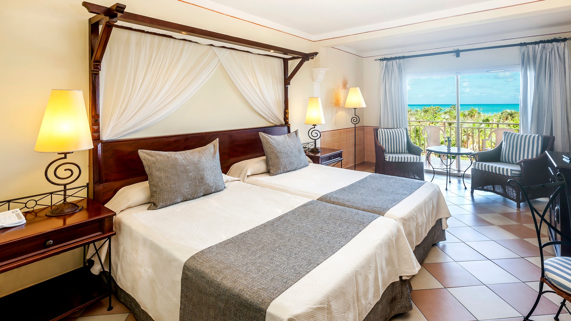 a room with two beds and a balcony overlooking the ocean