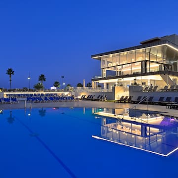 a pool with a building and a building with a pool and palm trees