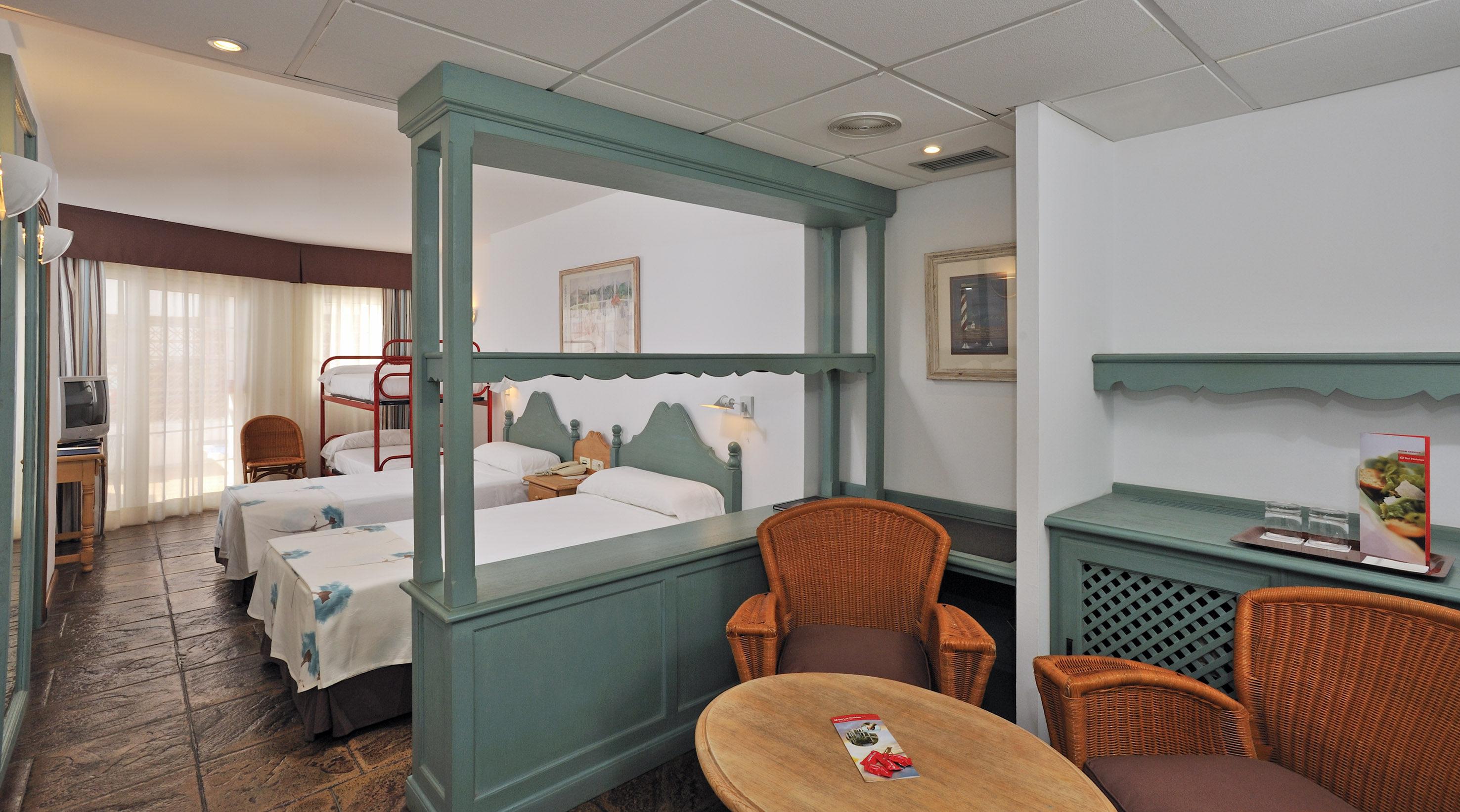 Hotel family room with twin beds, bunk bed, and teal room divider.