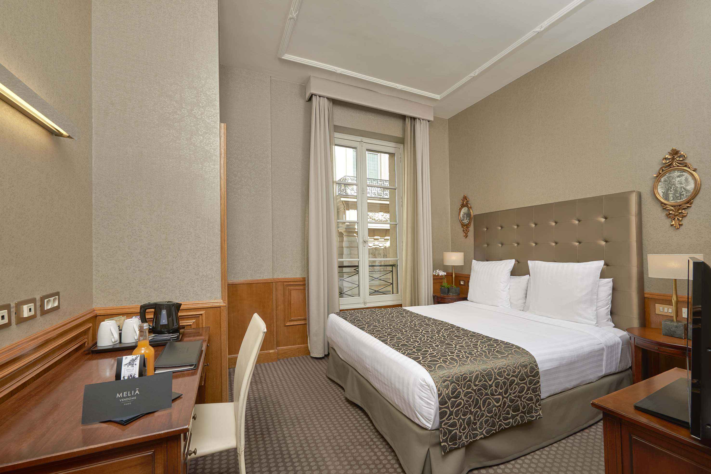 Melia Vendome Paris hotel room with comfortable bed, desk, and window.