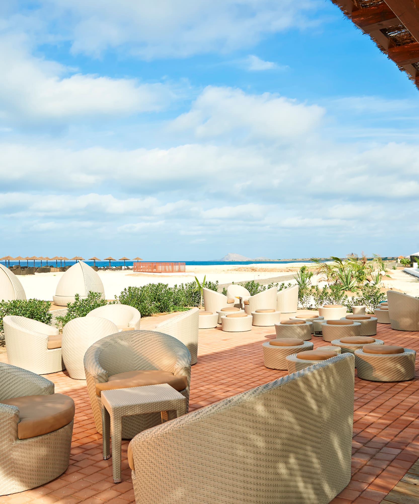 a patio with chairs and a beach view