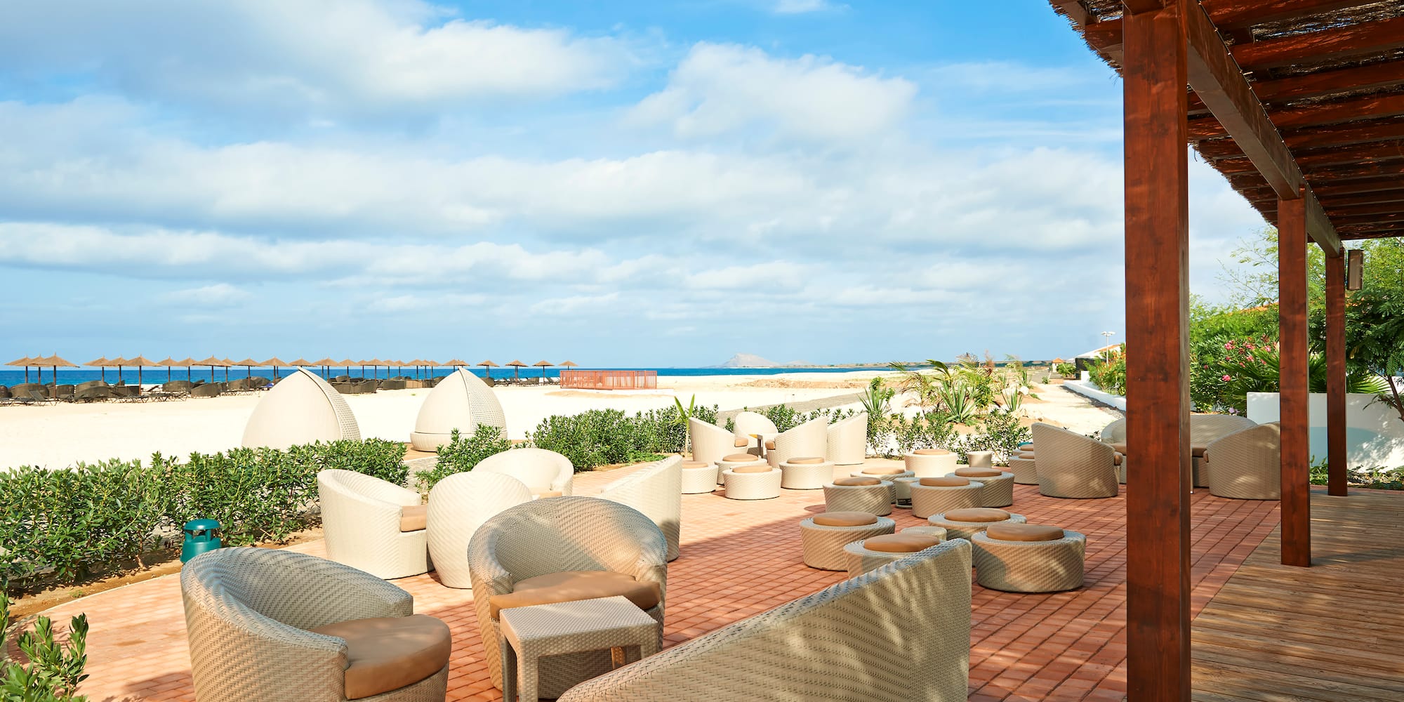 a patio with chairs and a beach view