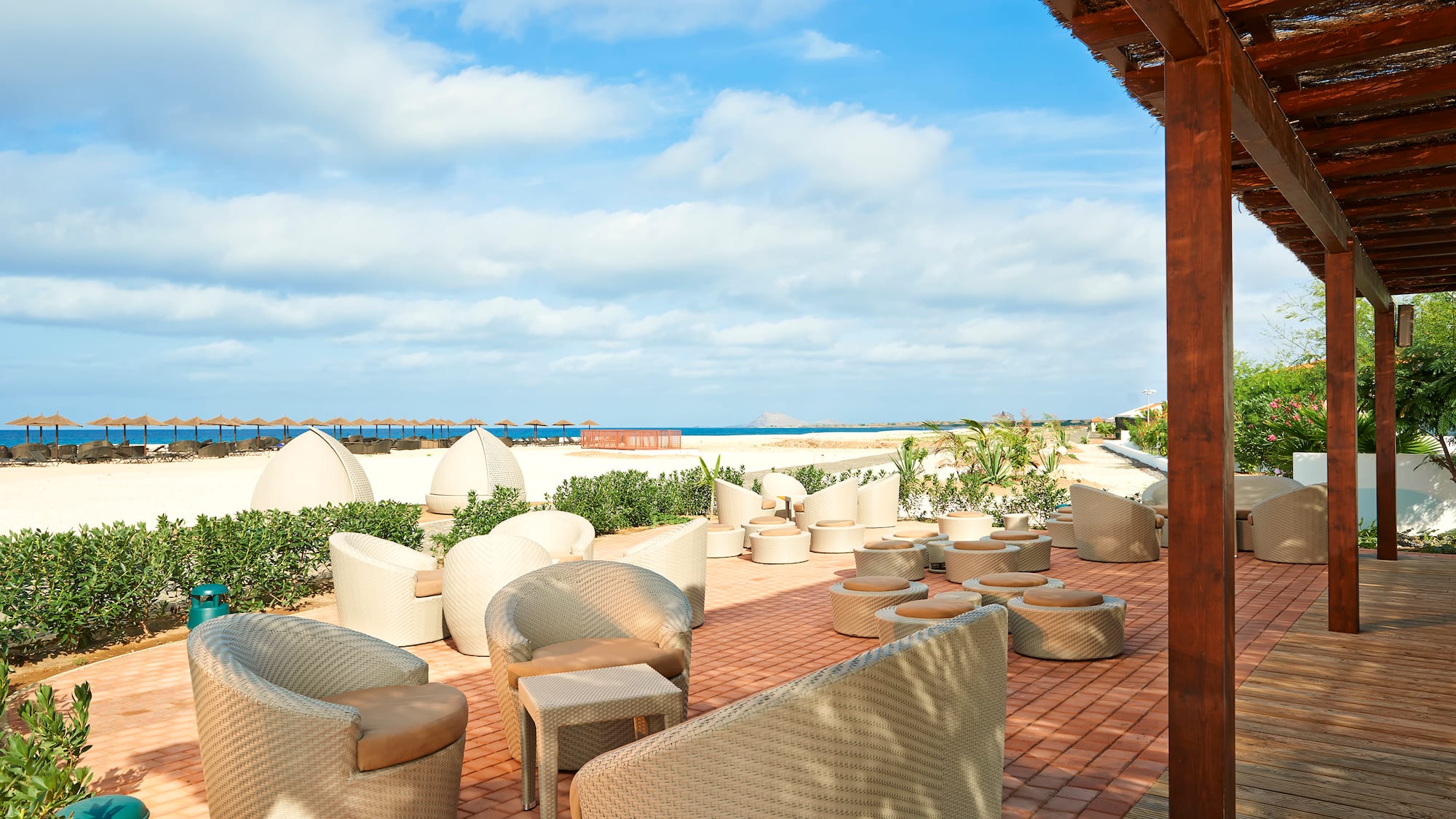 a patio with chairs and a beach view