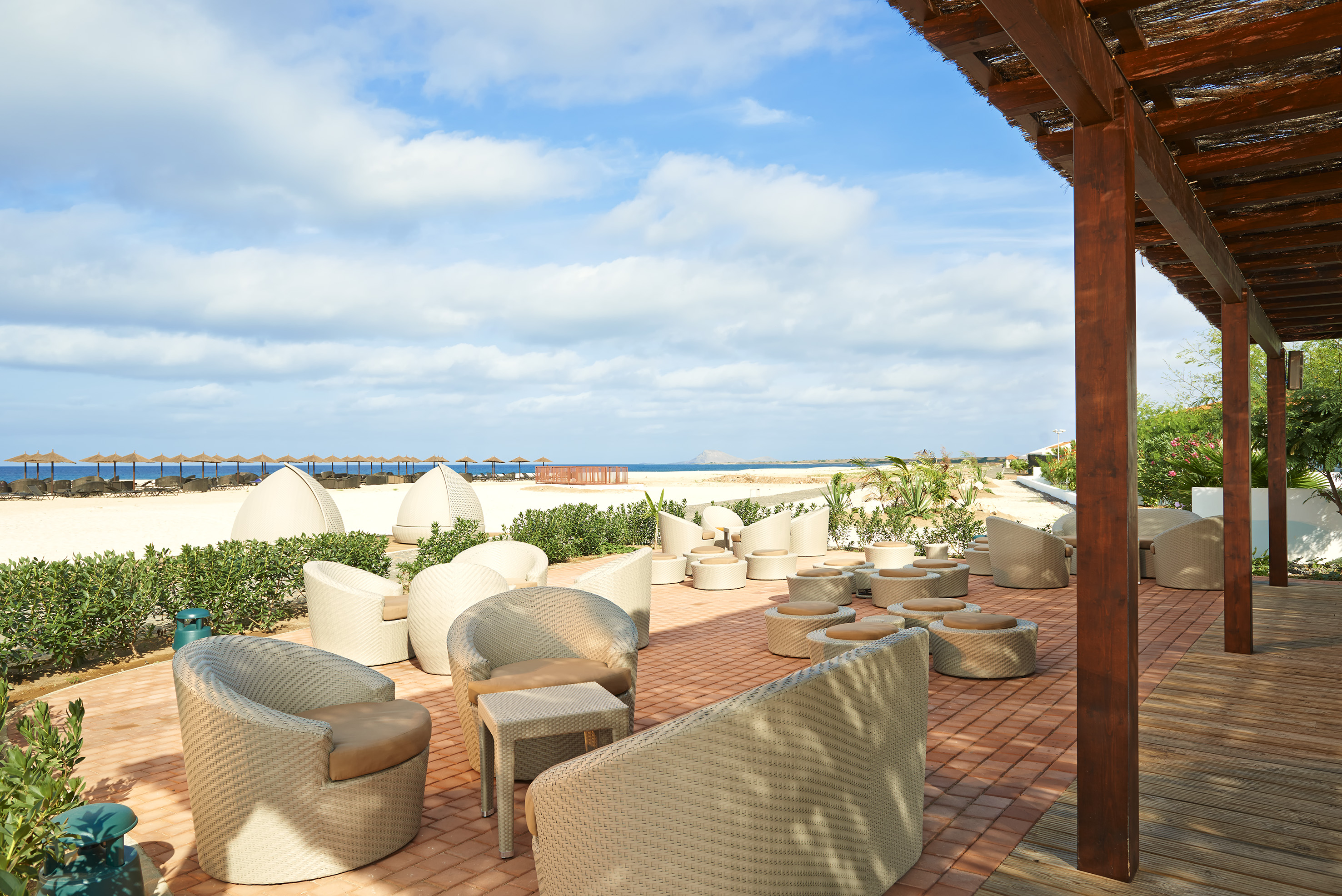 a patio with chairs and a beach view