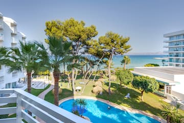 a pool in a resort with trees and a body of water