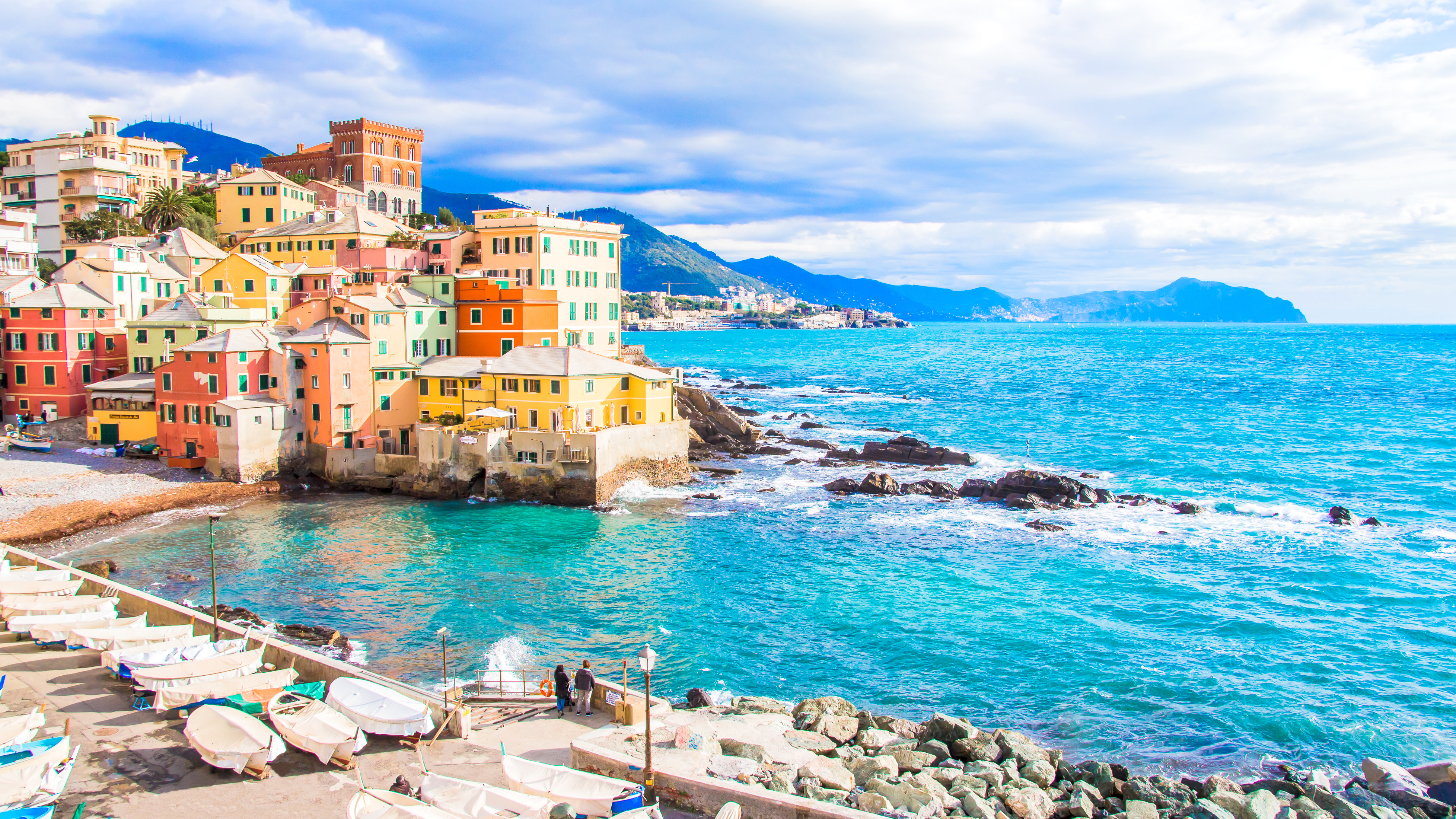 a colorful buildings next to a body of water with Cinque Terre in the background