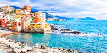 a colorful buildings next to a body of water with Cinque Terre in the background