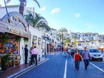 people walking on a street with buildings and palm trees