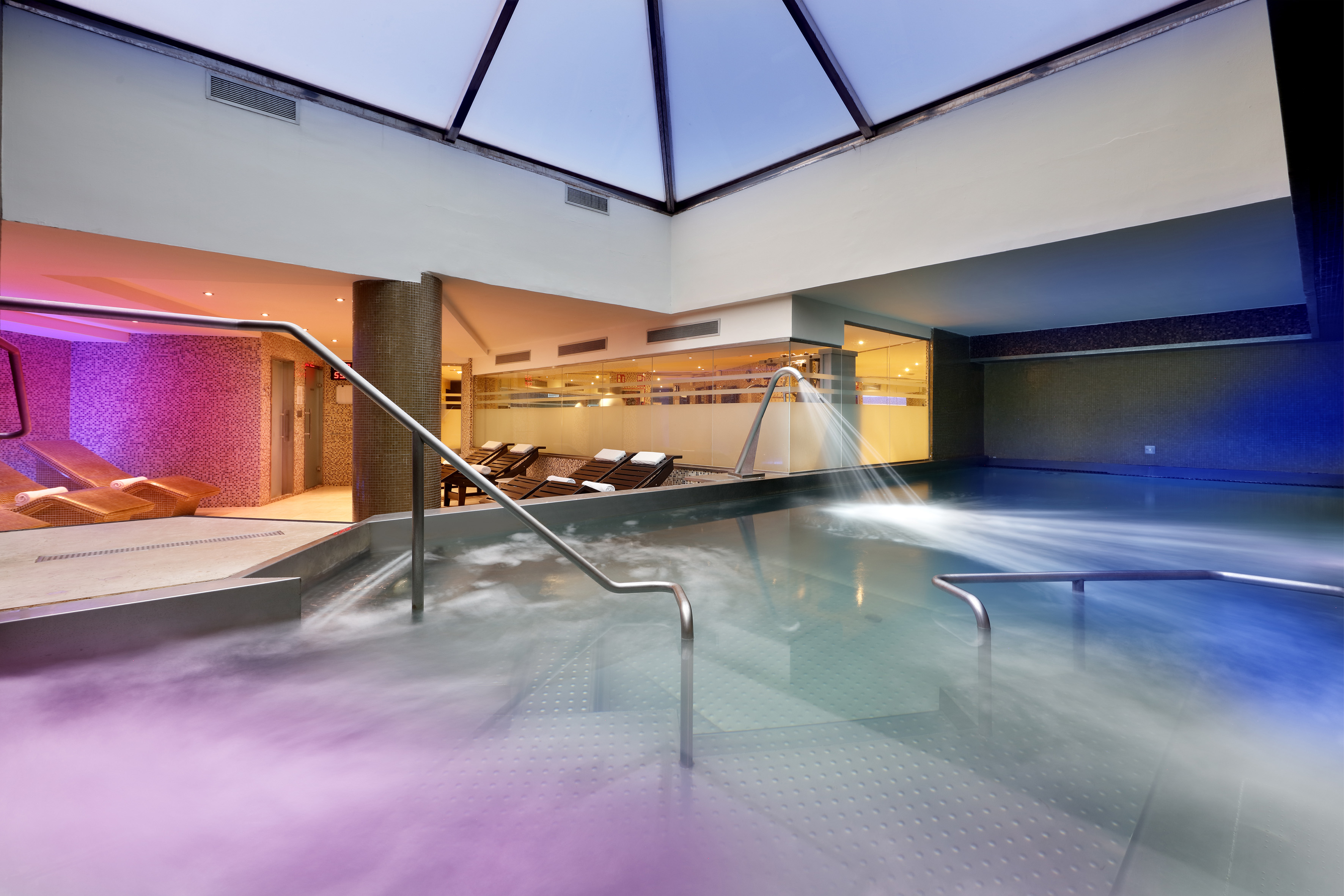 Indoor spa pool with hydrotherapy jets, mood lighting, and comfortable loungers.