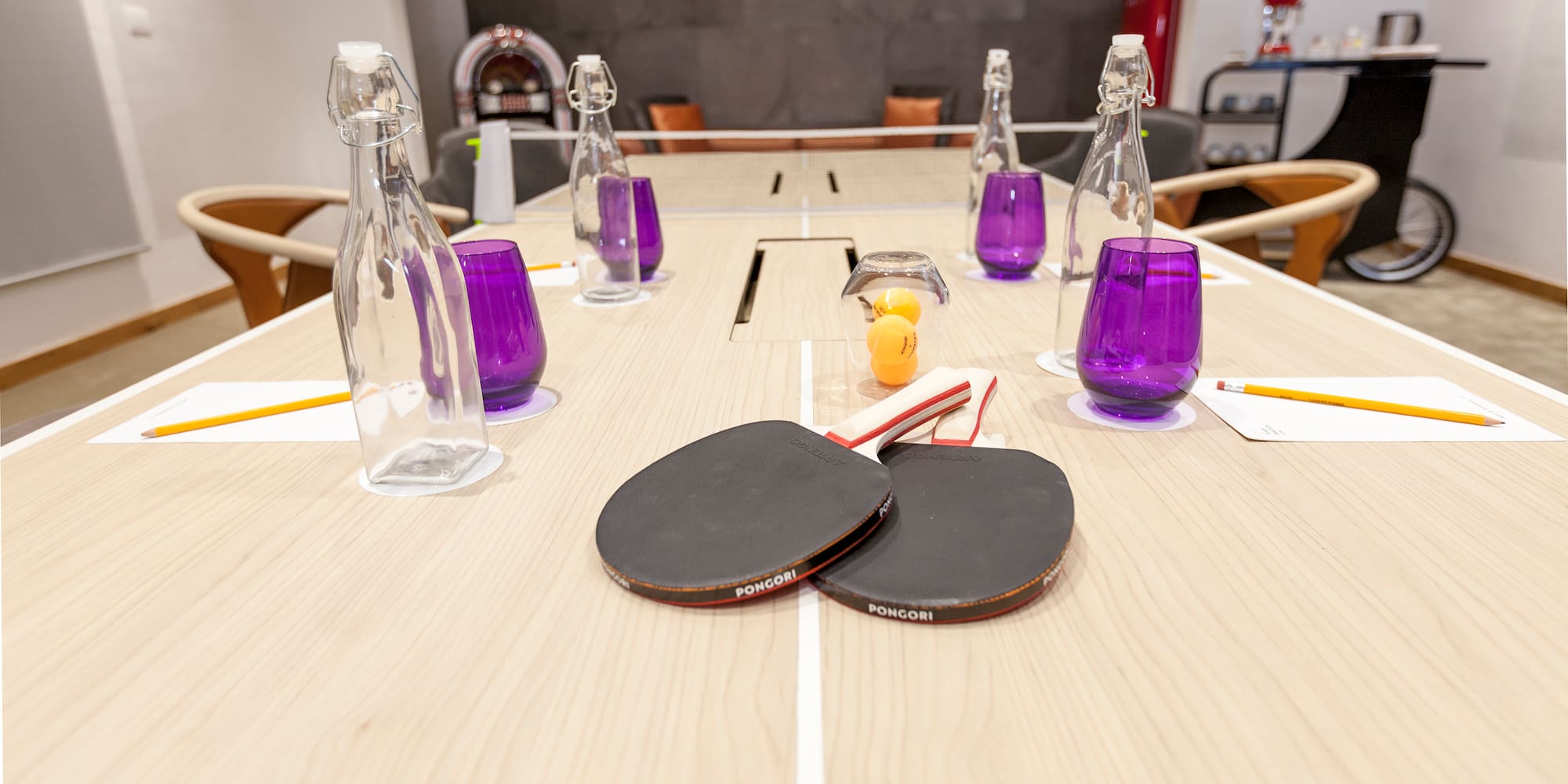 a table with ping pong paddles and purple glasses