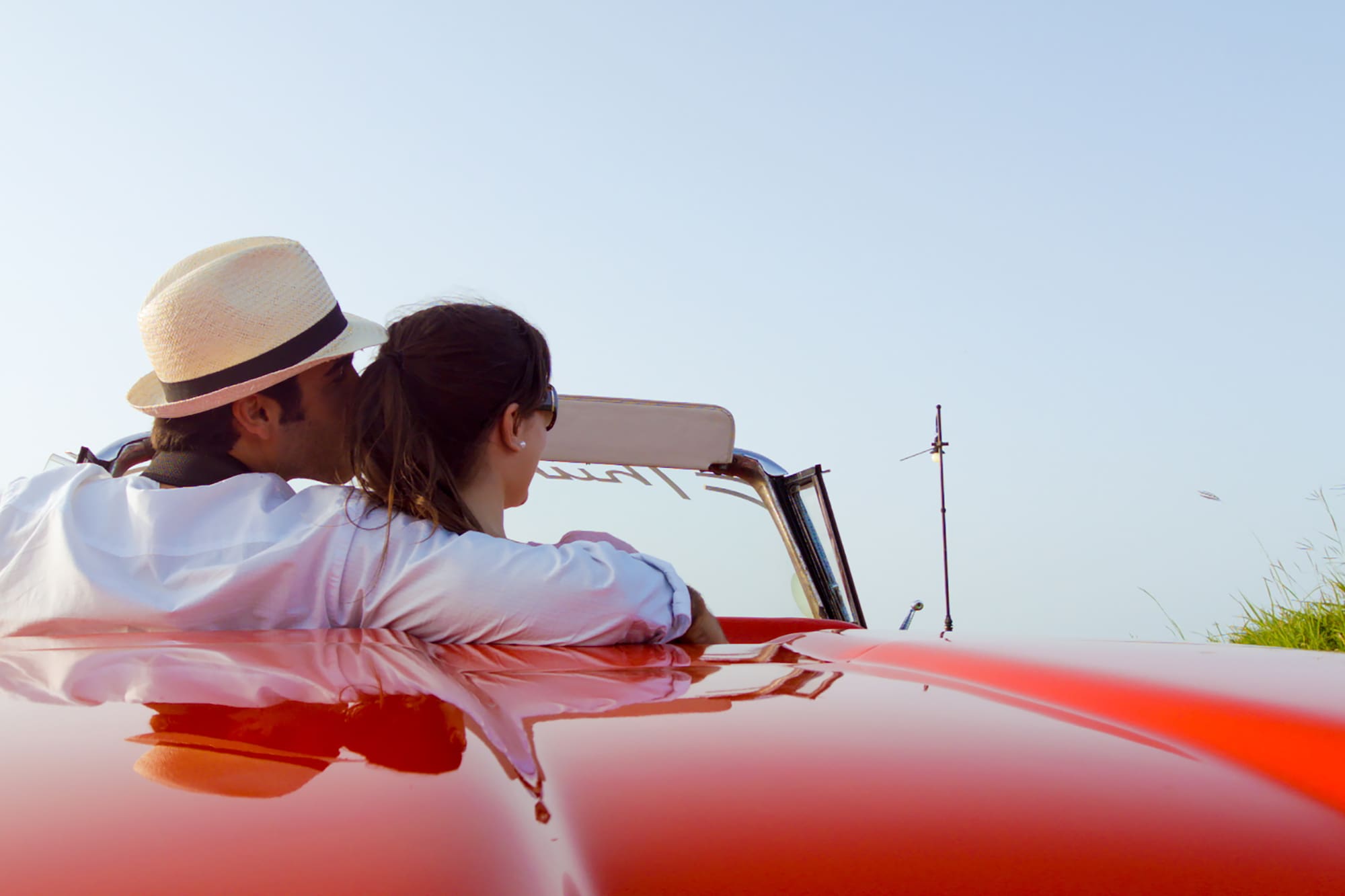 a man and woman sitting on a red car